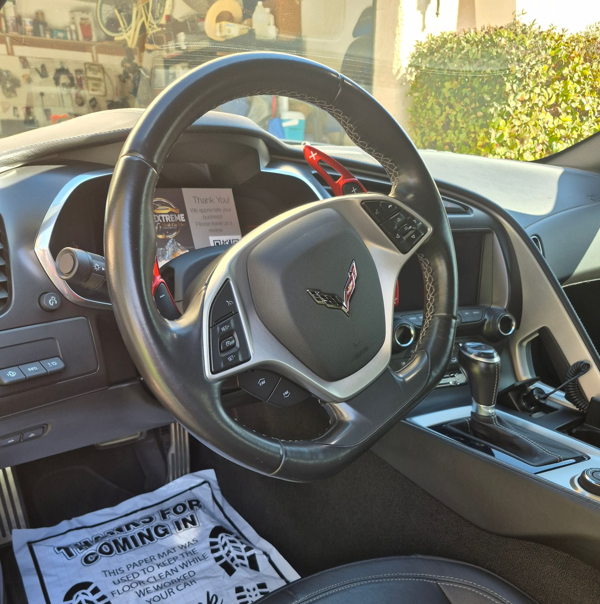 Luxury sports car interior with black leather steering wheel and center console in sunlight