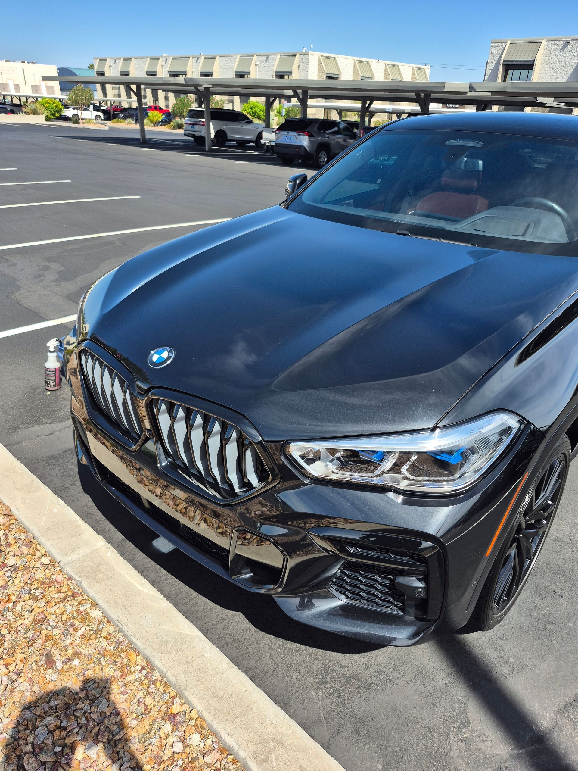 Black BMW sedan parked in a lot on a sunny day, front view close-up.