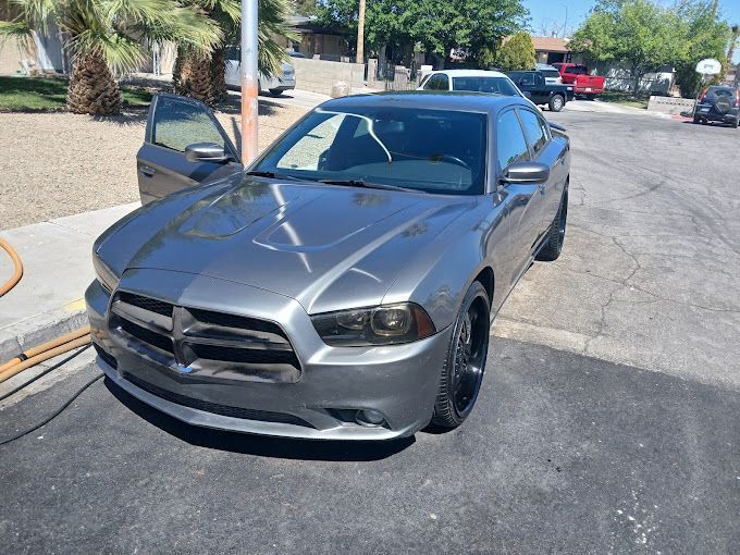 Gray Dodge Charger parked on a street with the driver-side door open.