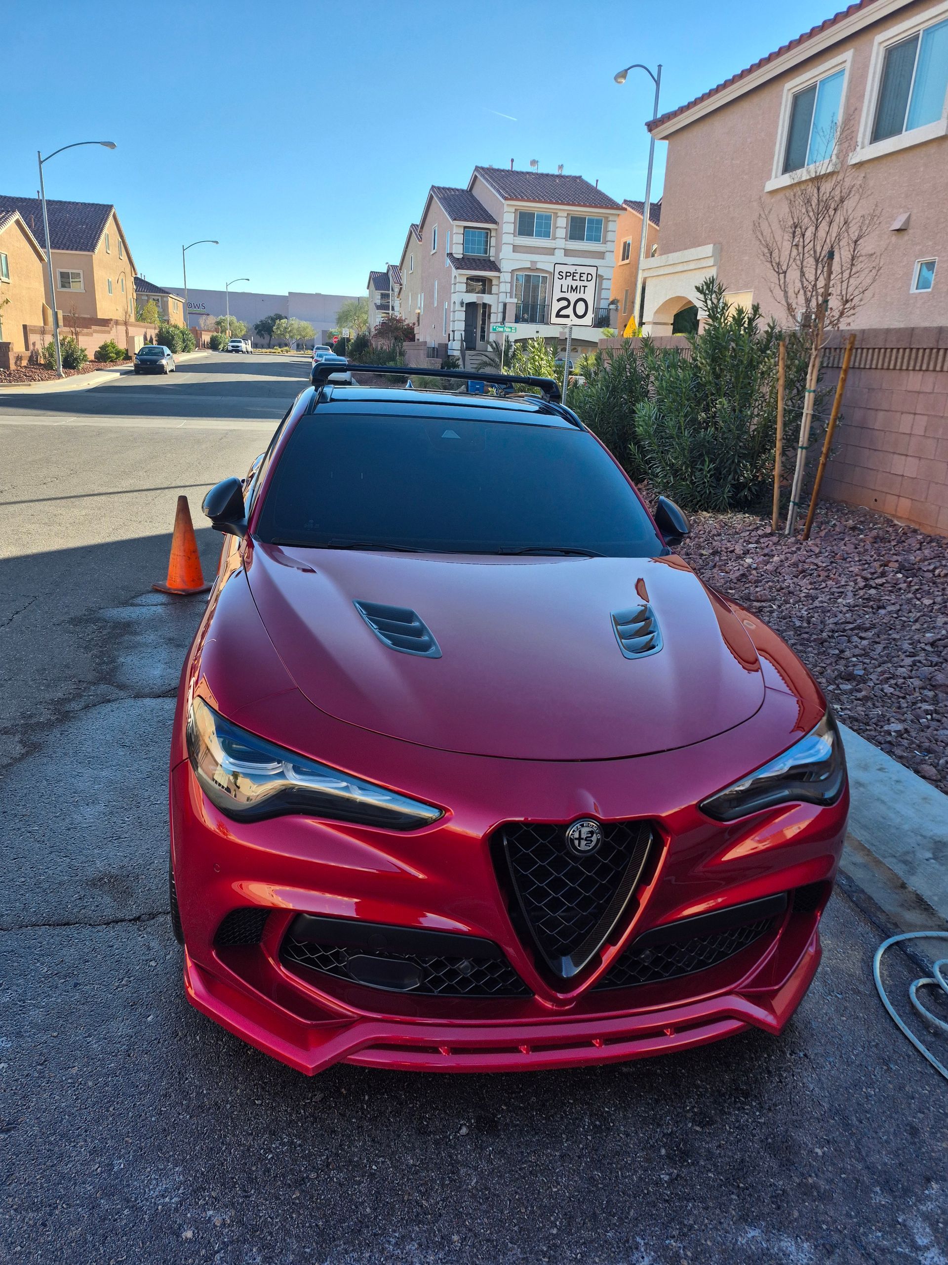 Red sports sedan parked on a residential street under a clear blue sky