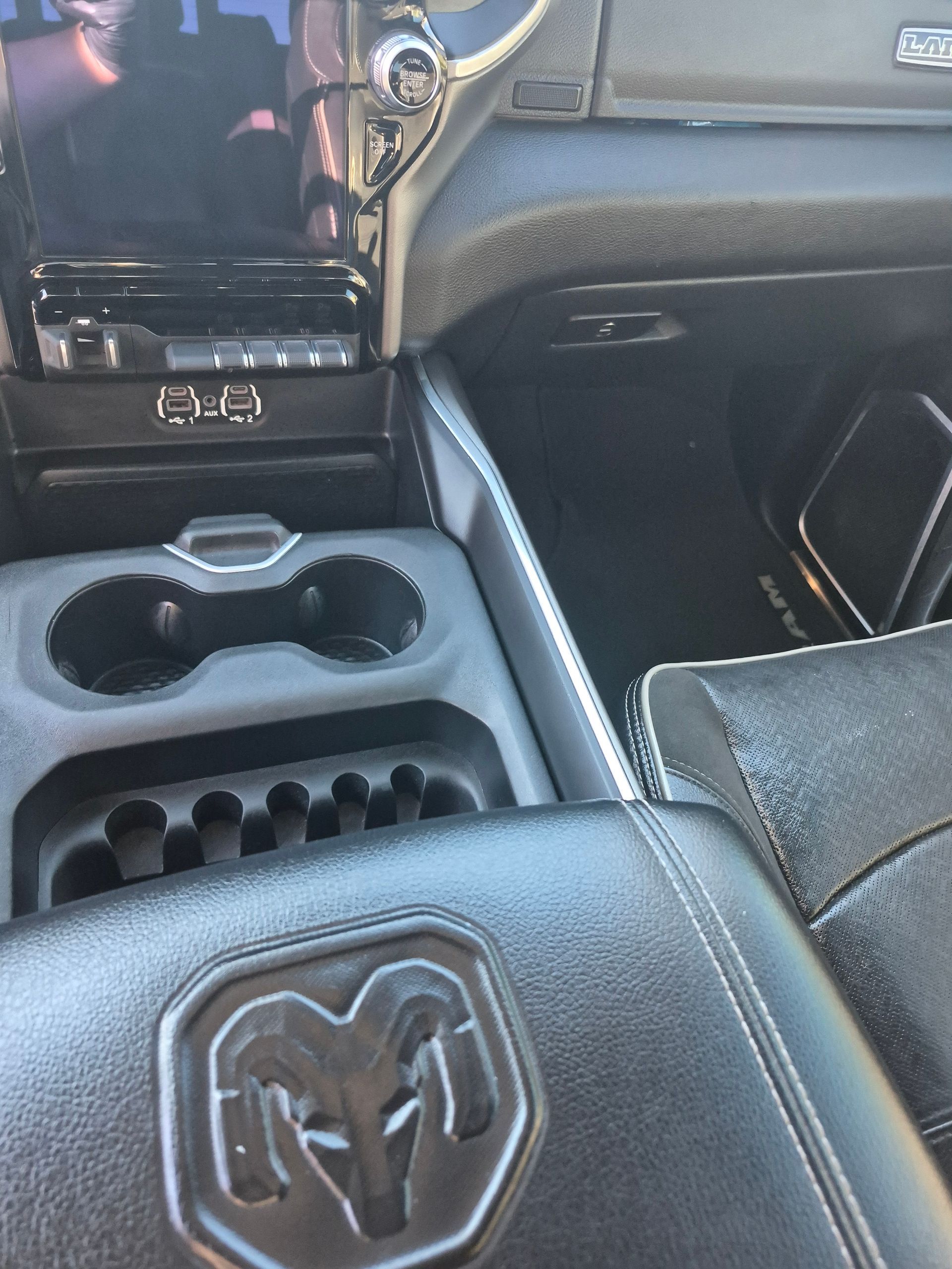 Black RAM truck center console with cup holders and stitched leather armrest.