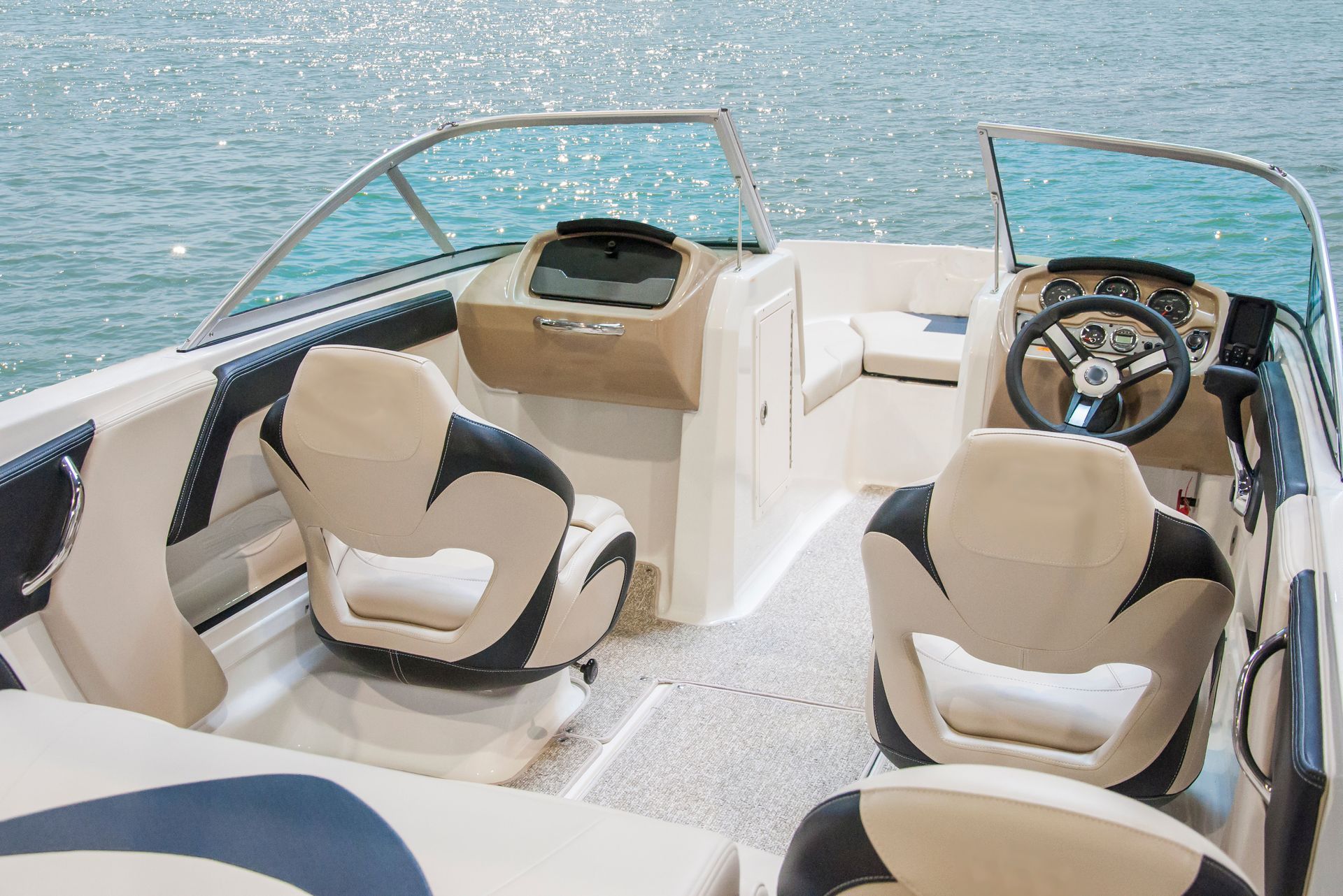 Boat cockpit with beige seats and steering wheel on open water