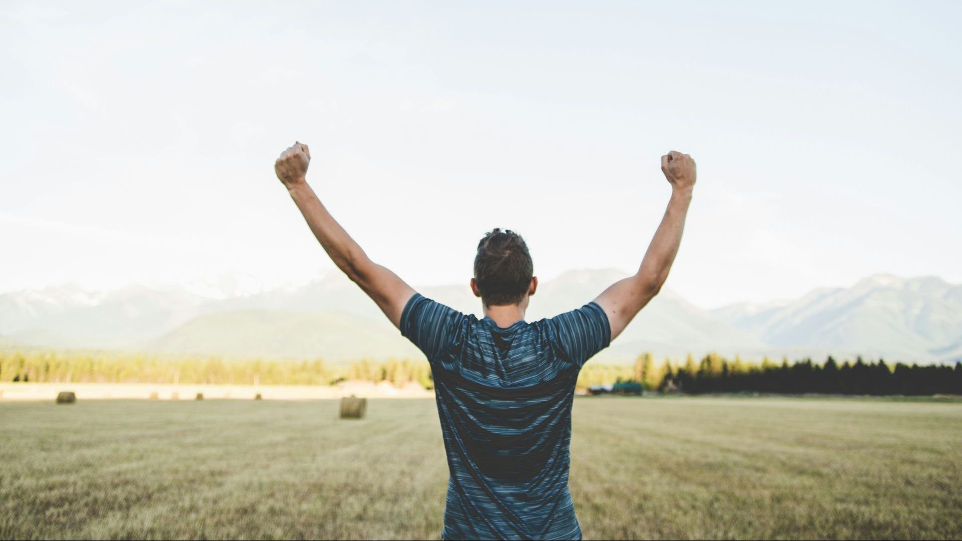 A man is standing in a field with his arms in the air.
