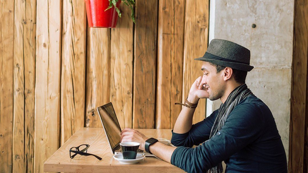 Man sitting at a table using a laptop computer.