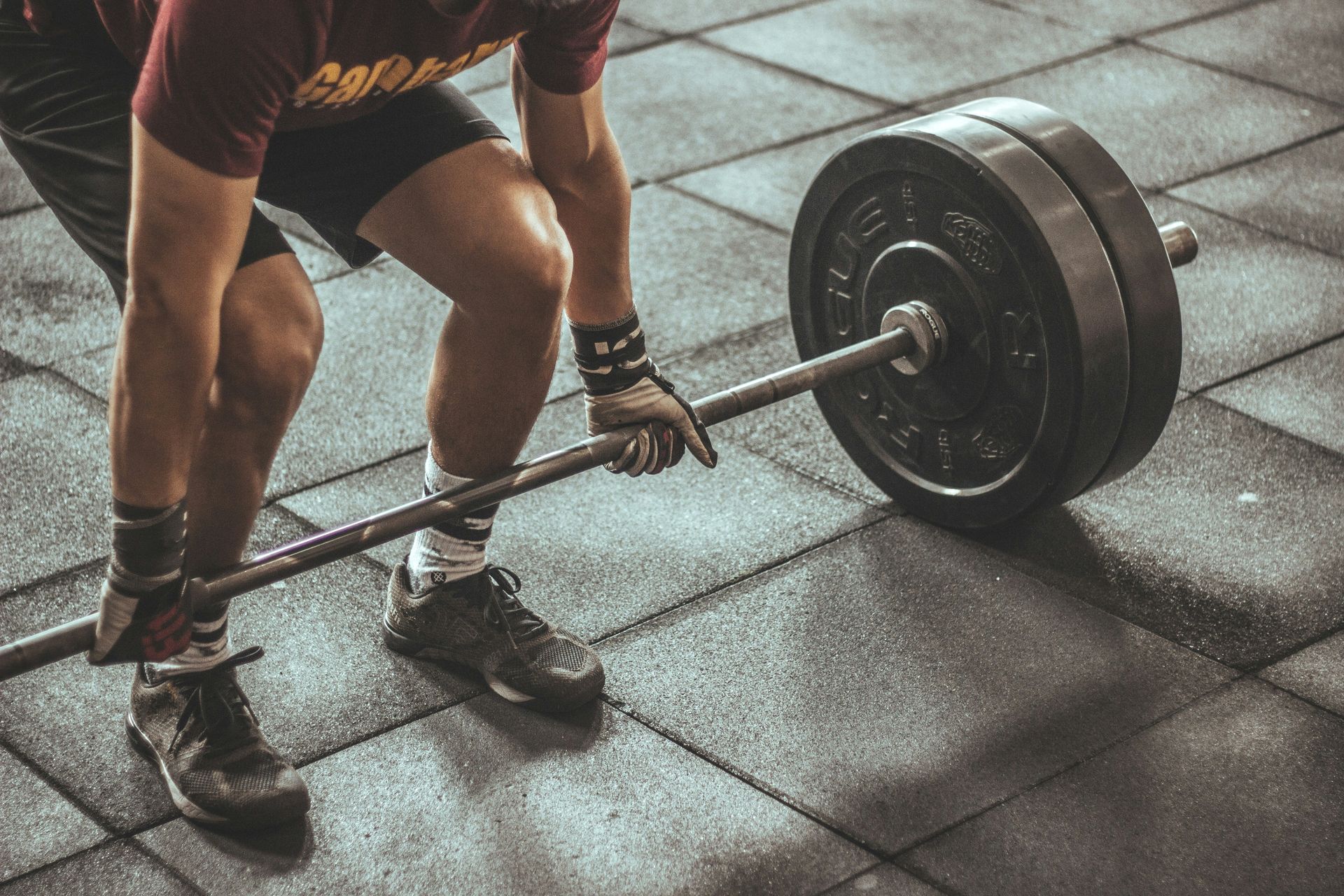 A man is lifting a barbell in a gym.