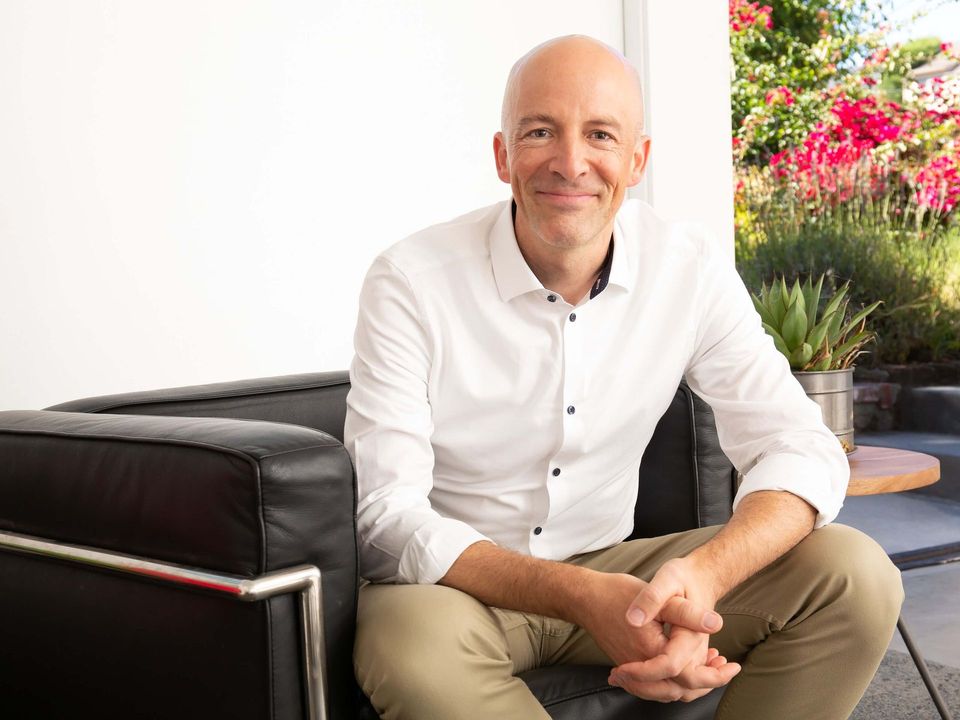 Berkeley therapist for men, Michael Ceely, smiling, seated on a black couch.