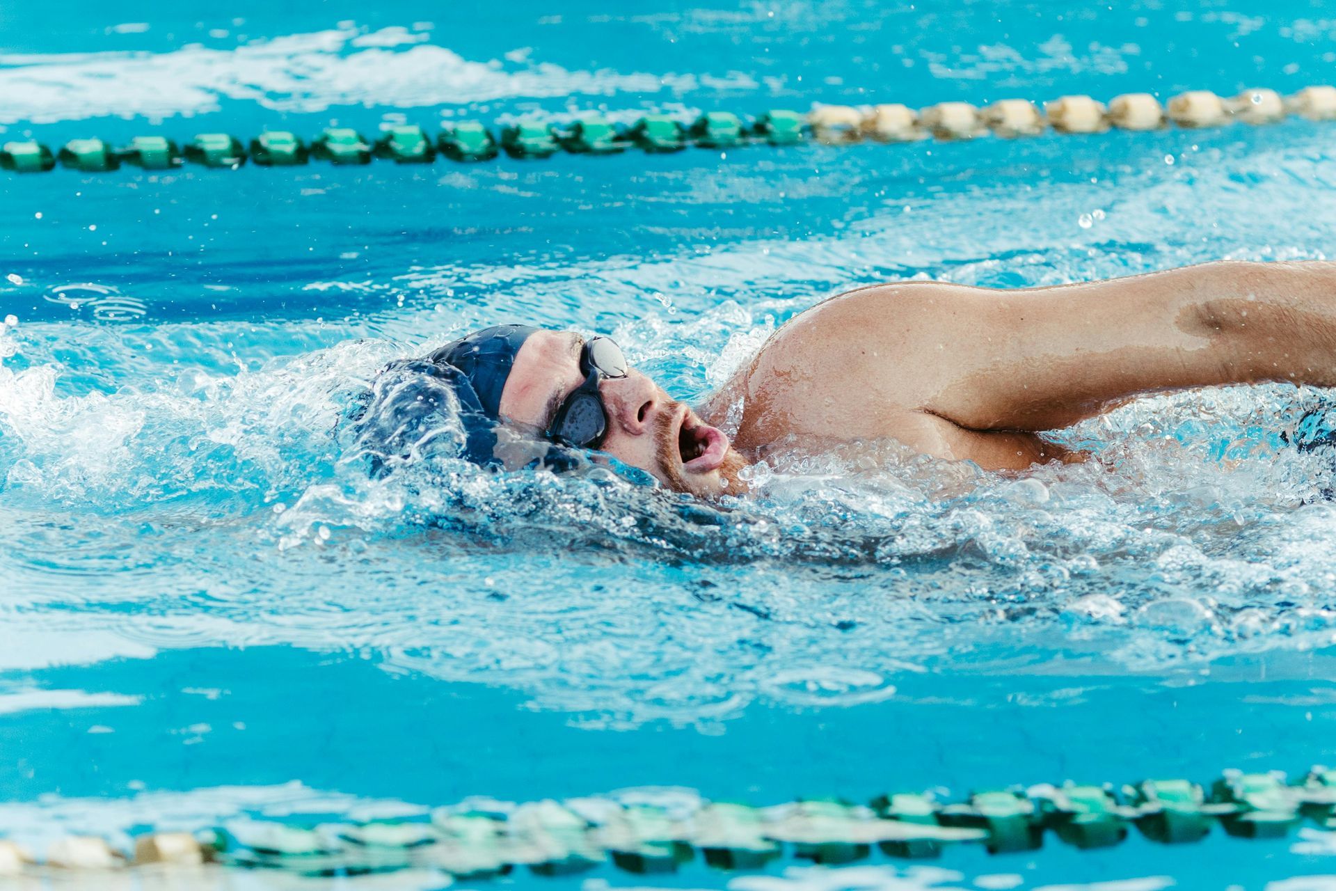 A man is swimming freestyle in a swimming pool.