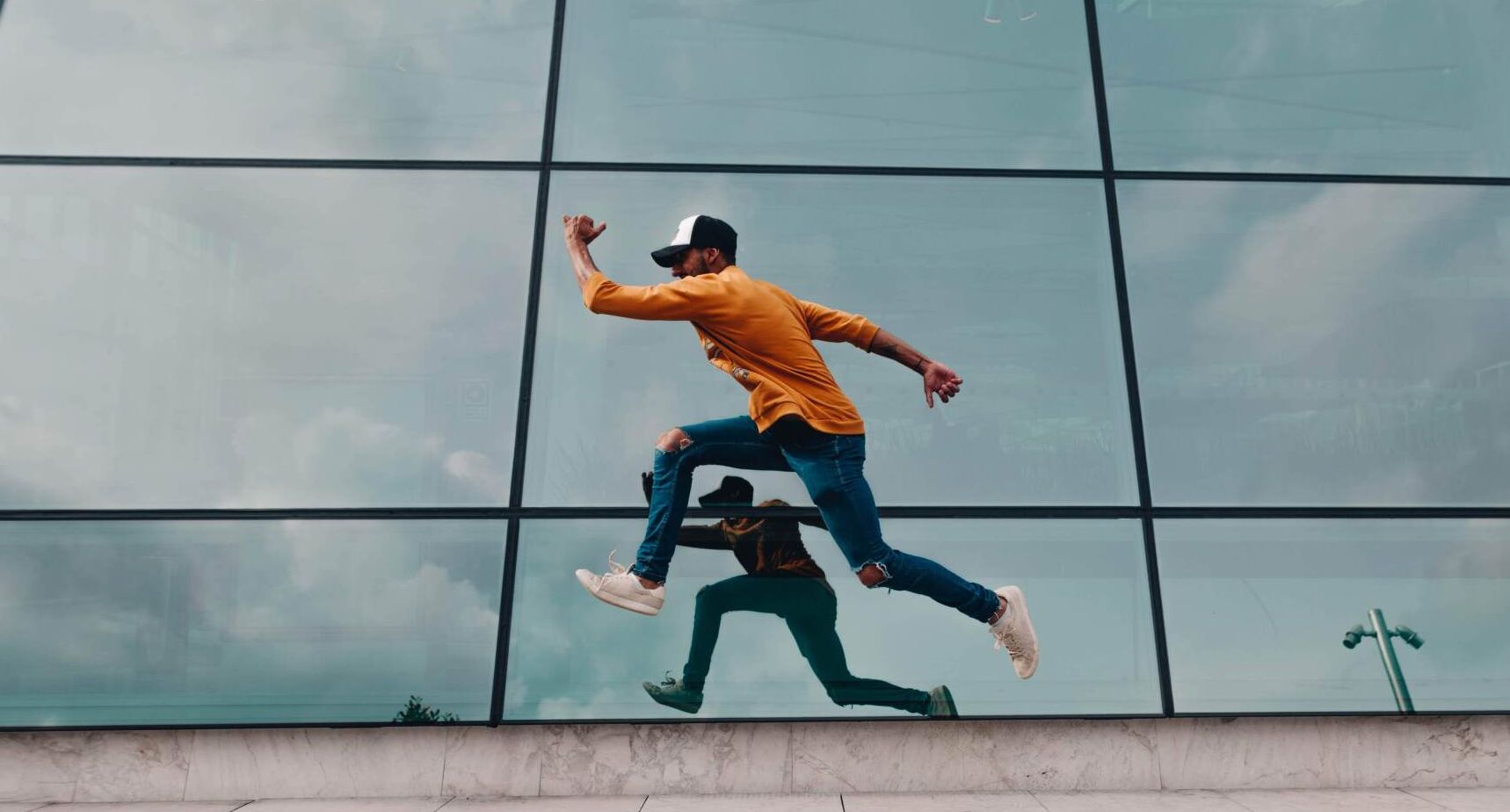 A man is jumping over a wall in front of a building.