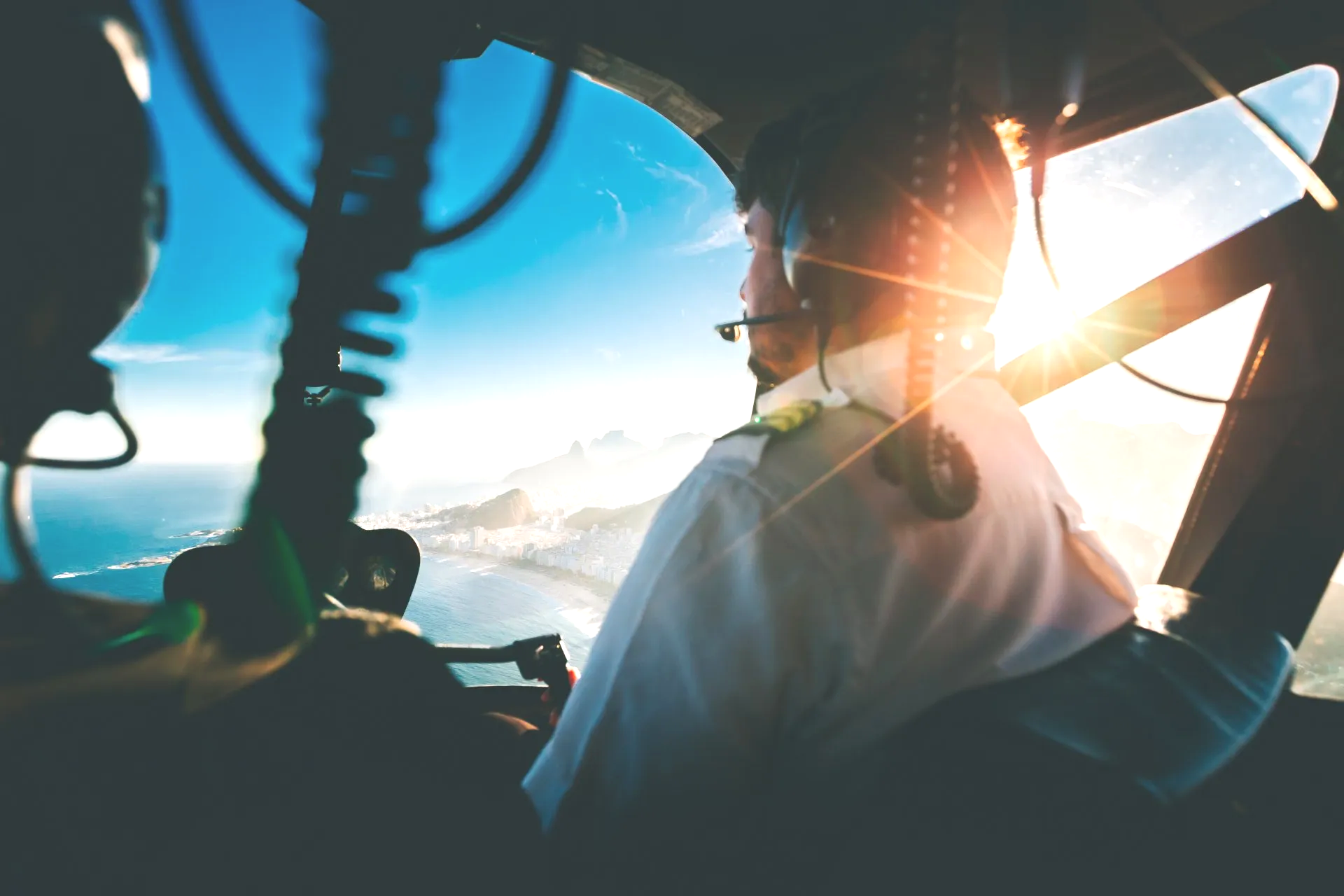 A pilot is sitting in the cockpit of a plane looking out the window.