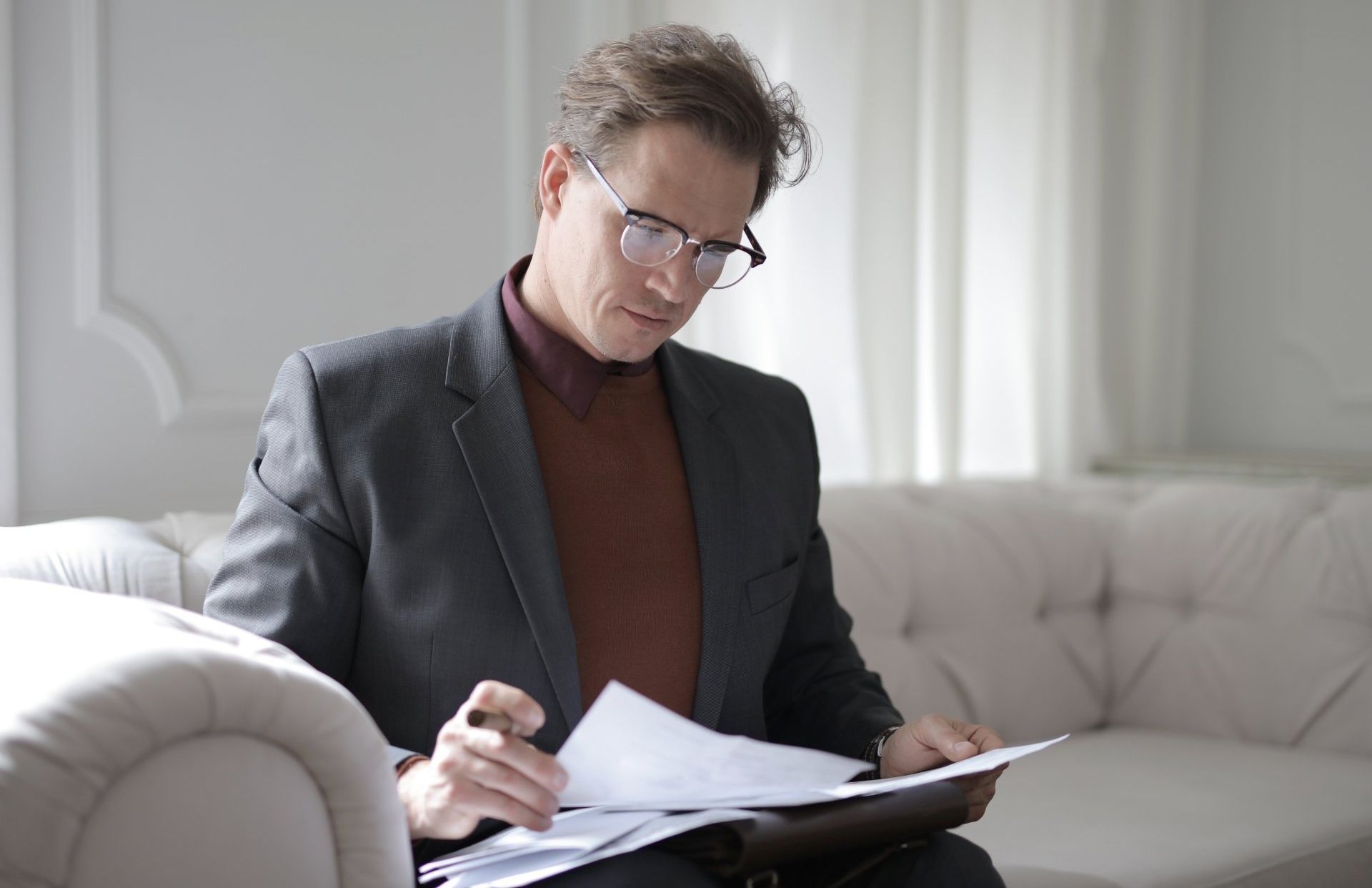 Man sitting on a couch looking at papers.