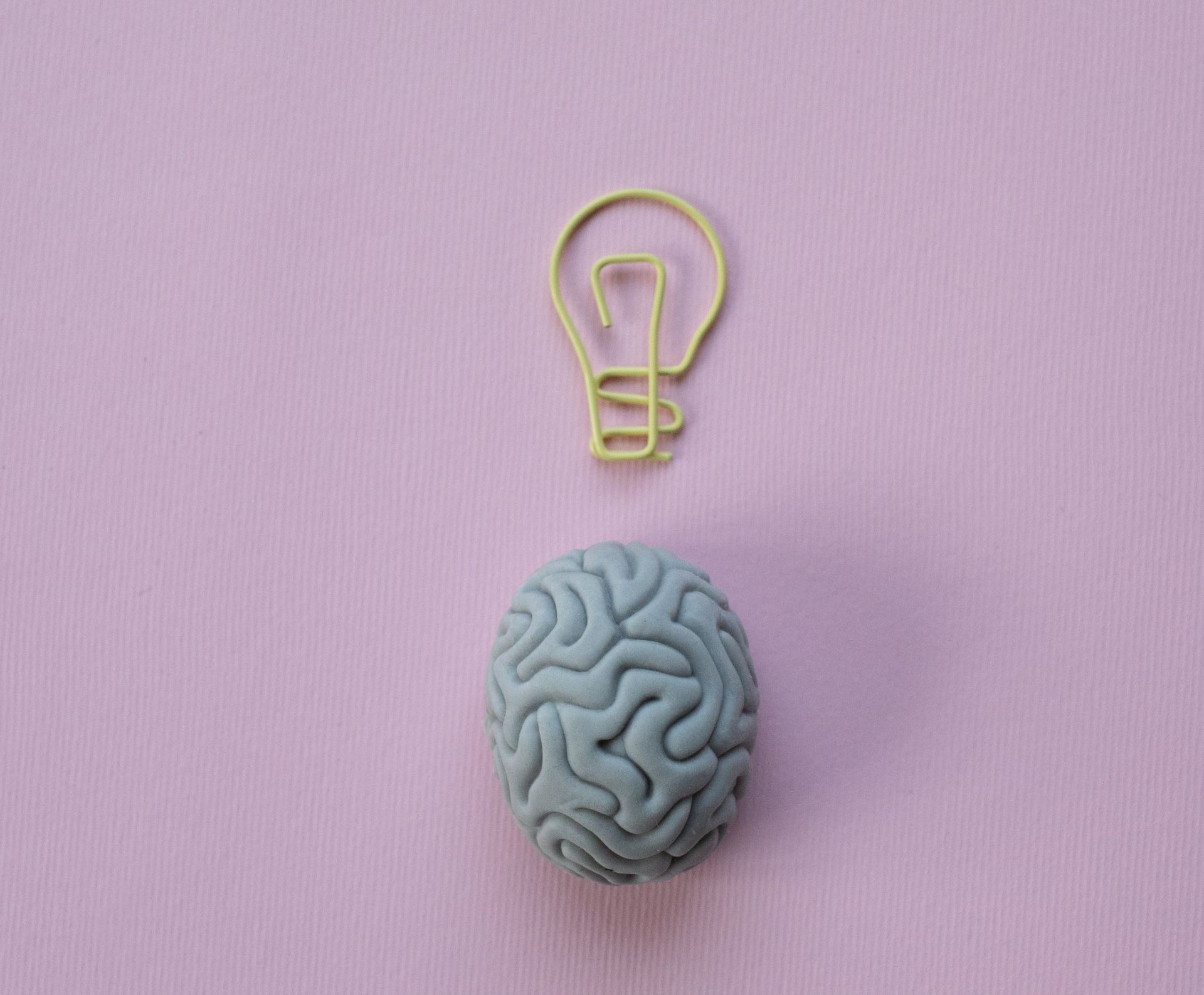 A brain and a light bulb on a pink background.