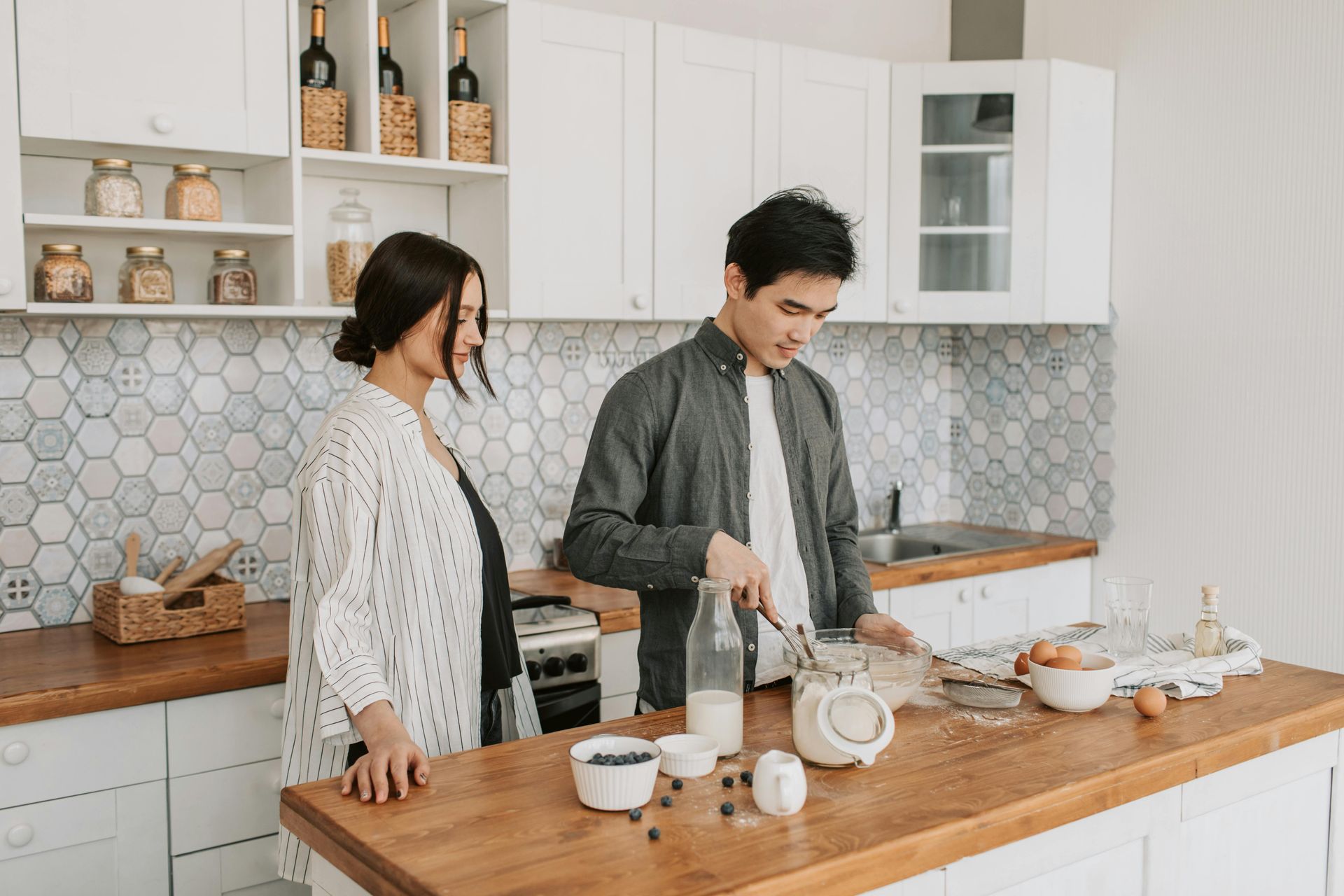 A man and a woman are preparing food in a kitchen.