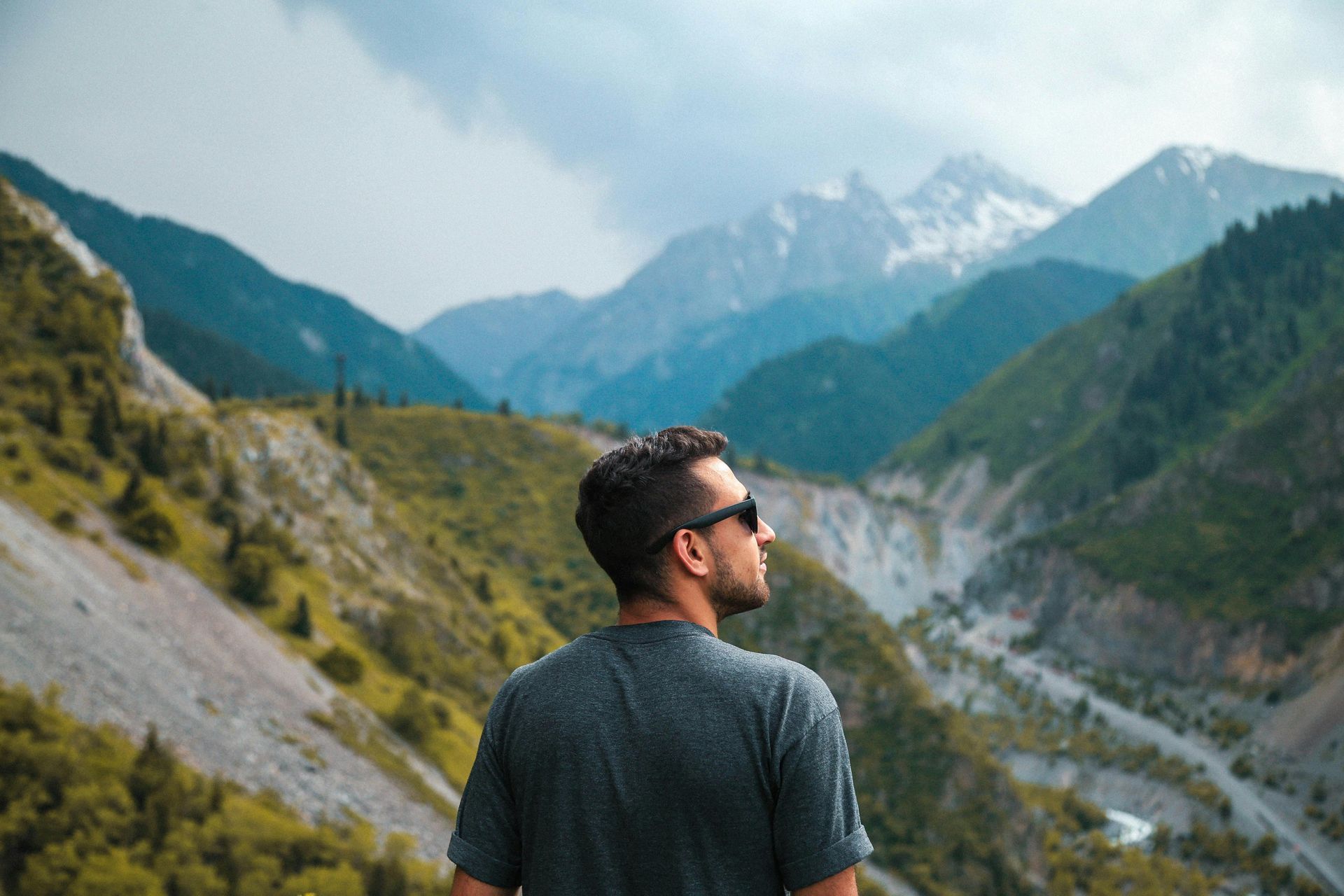 A man is standing on top of a mountain looking at the mountains.