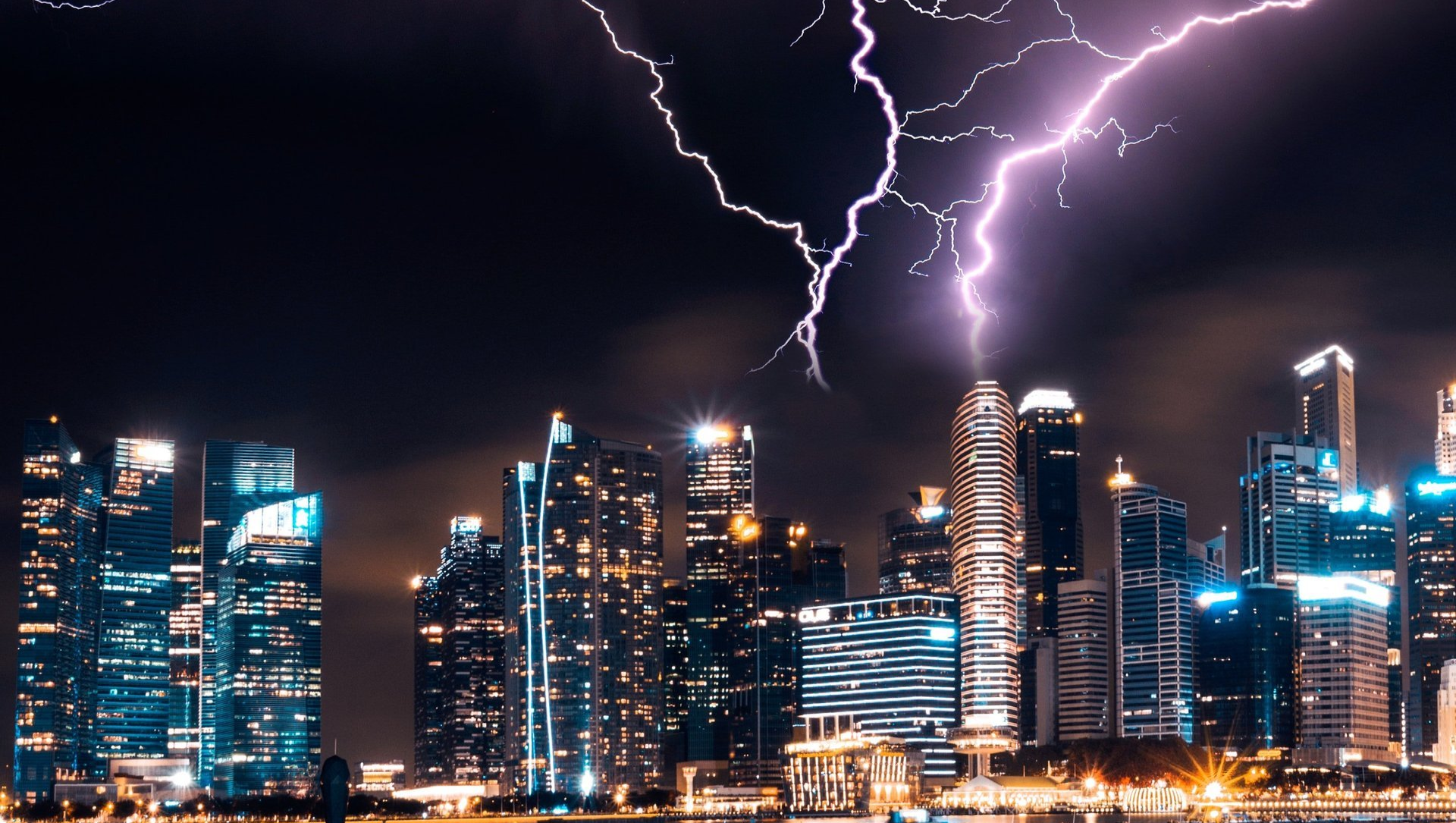 Lightning strikes over a city skyline at night