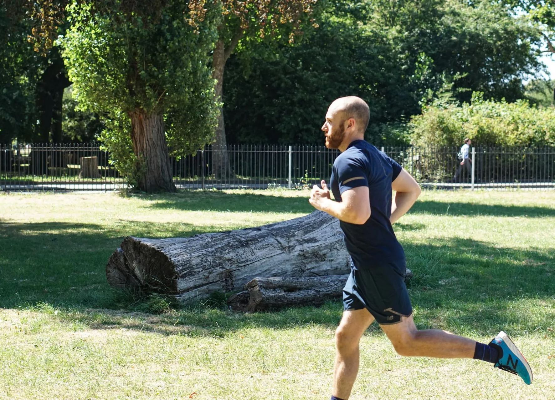 A man is running in a park next to a log.