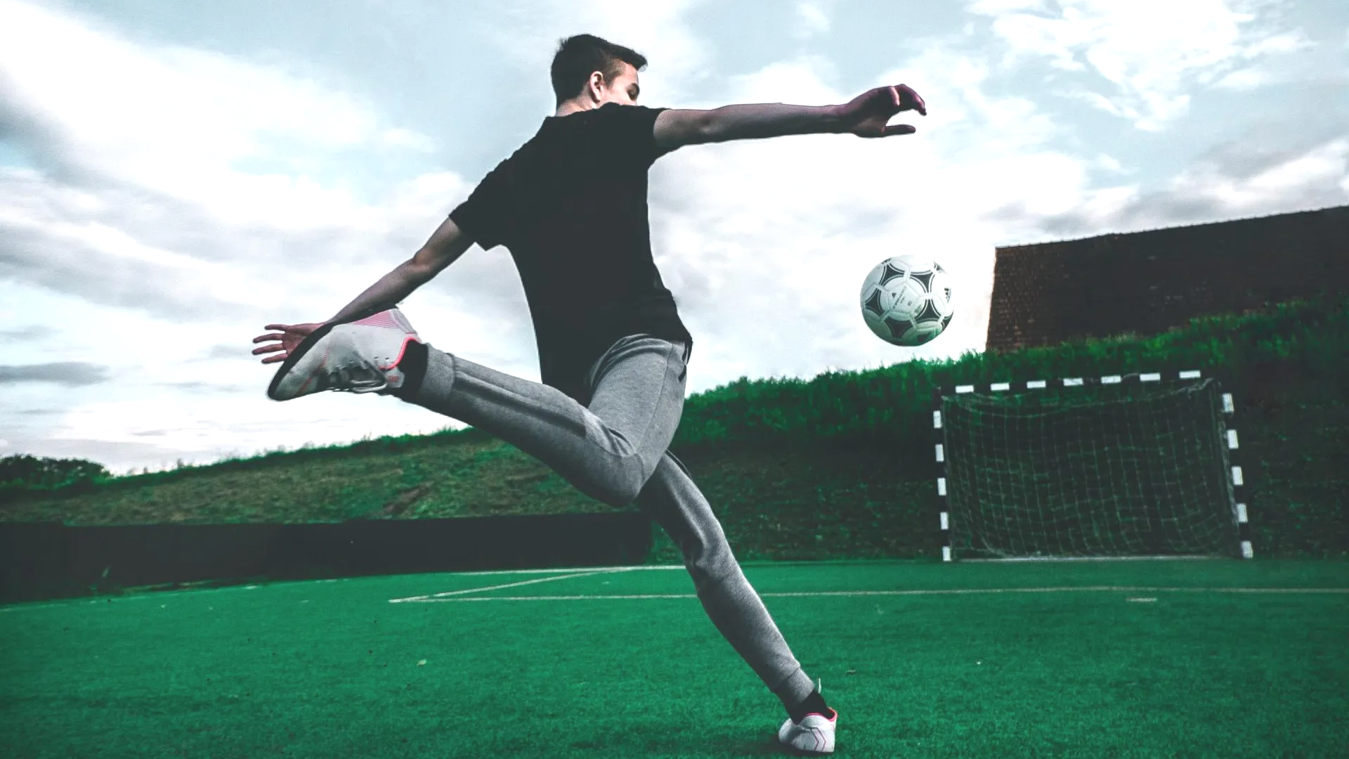 A man is kicking a soccer ball on a field.