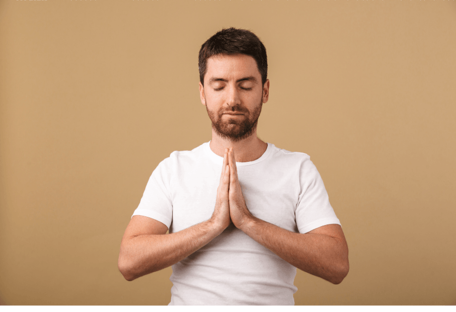 A man with a beard praying with his hands folded in front of his chest.