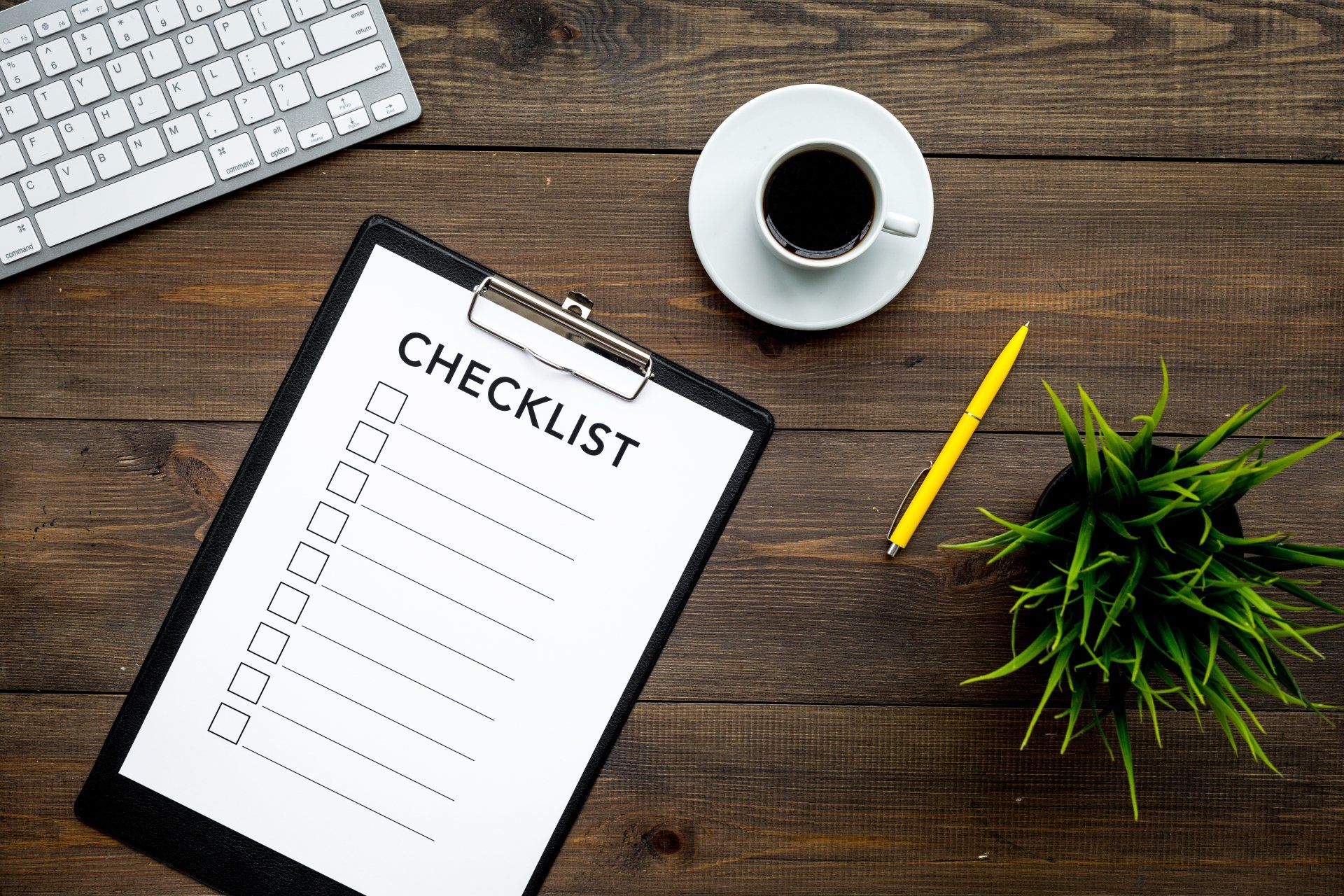 Checklist on a wooden desk next to a cup of coffee.