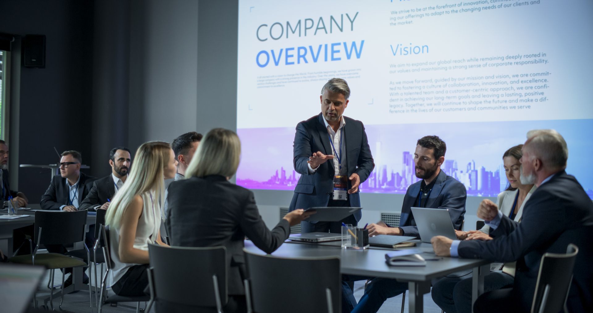 Business presentation: A man gestures toward a screen with 
