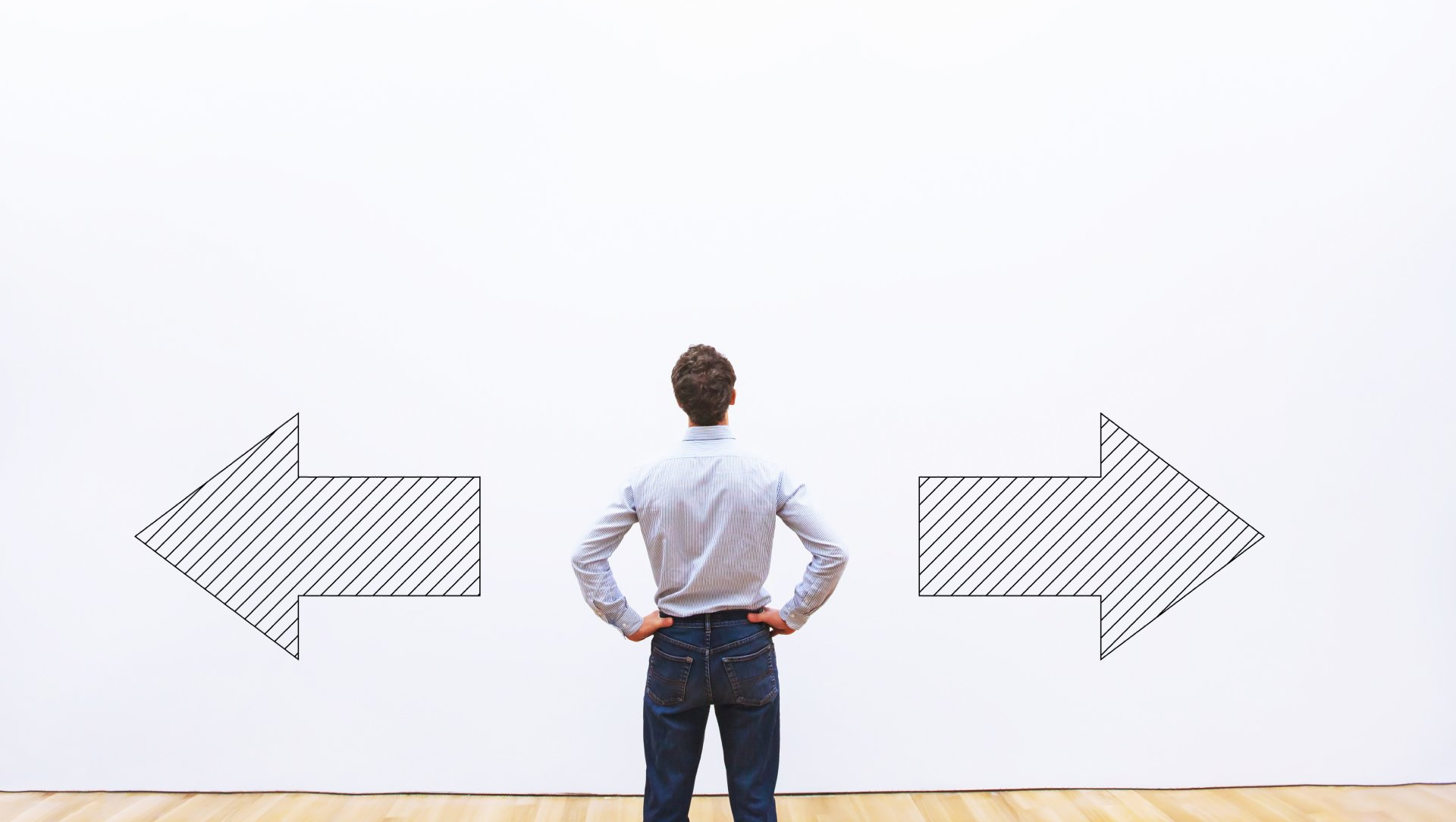 A man is standing in front of a wall with two arrows drawn on it.