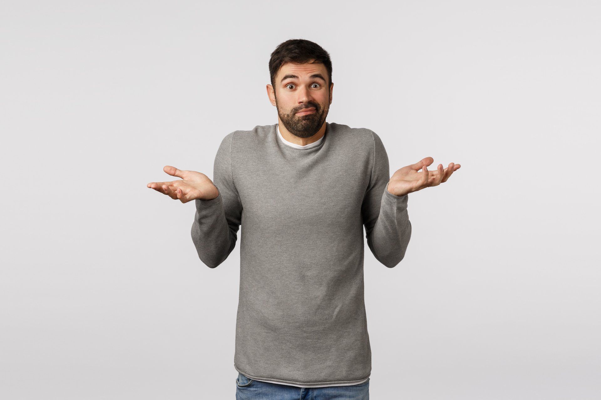 A man with a beard is shrugging his shoulders.