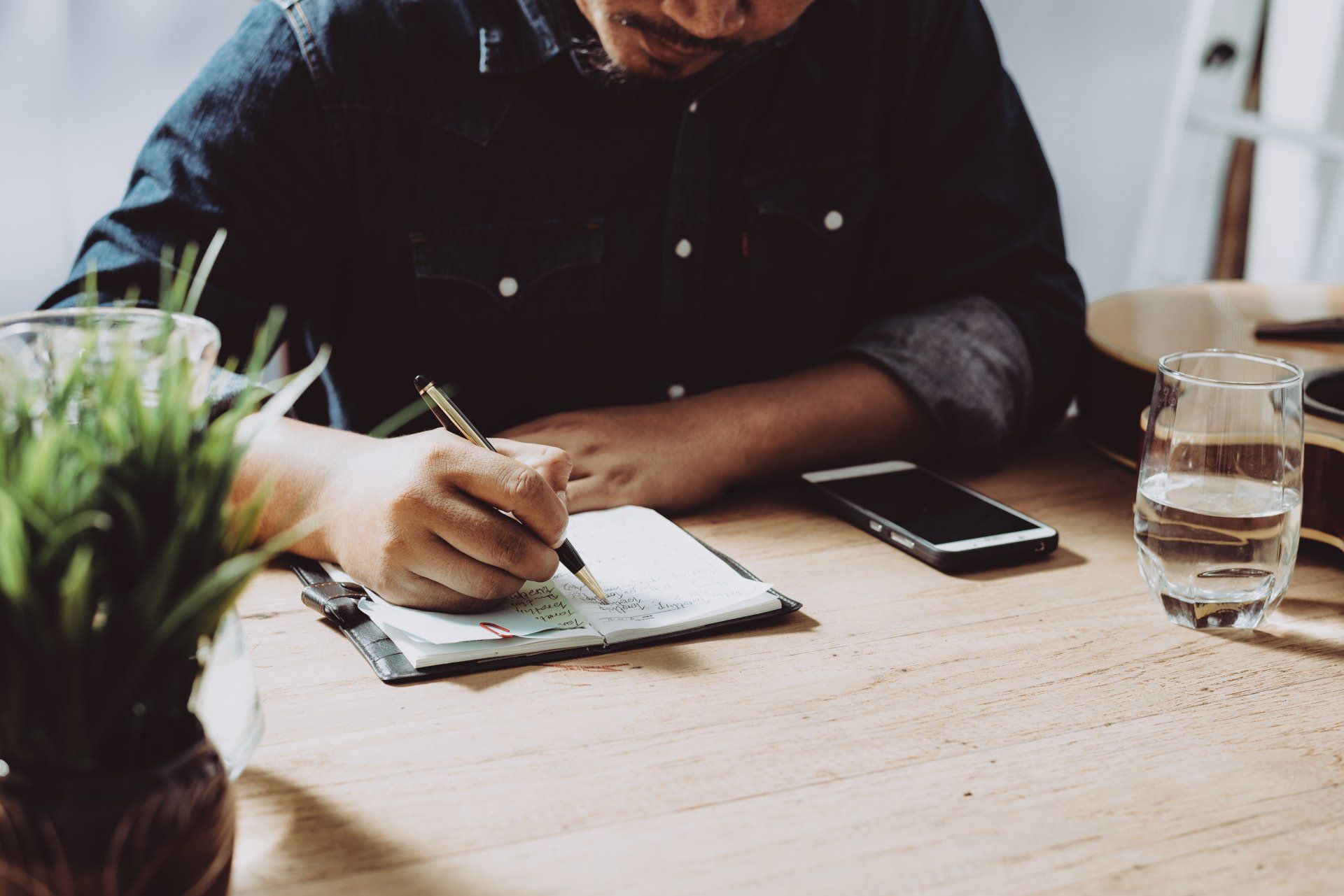 Man sitting at a table writing on a clipboard.