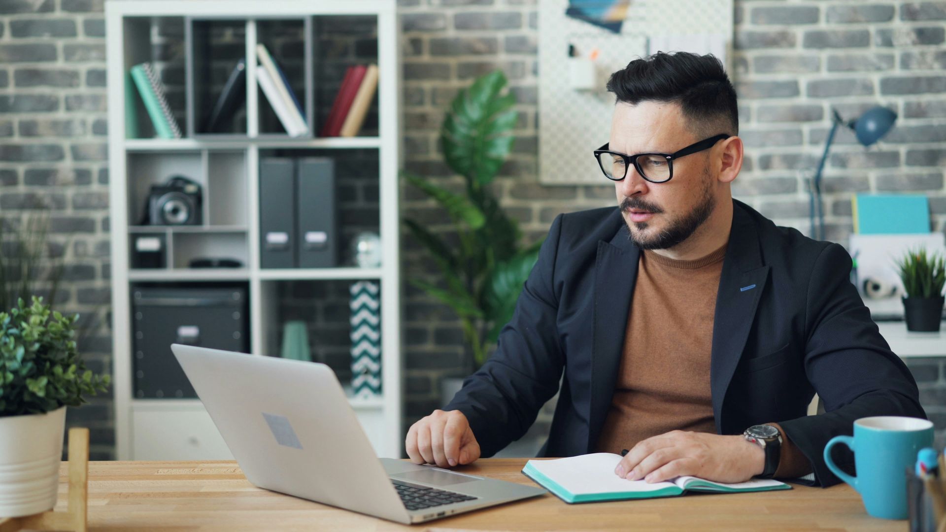 A man sitting at a desk using a laptop computer.