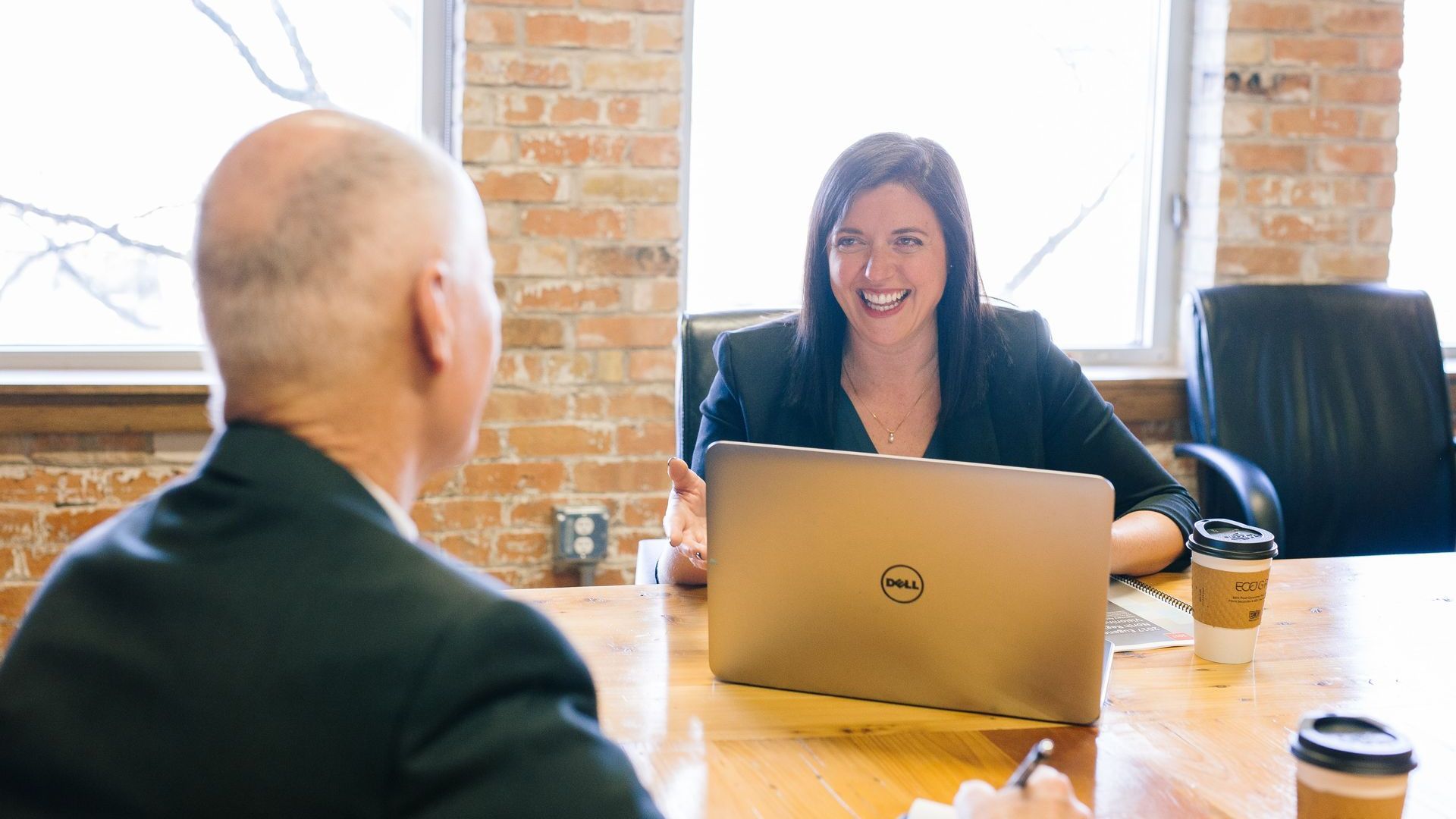 Man and a woman talking at a table with a laptop