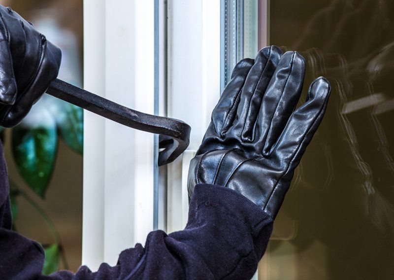 Einbrecher öffnet Fenster mit einem Brecheisen