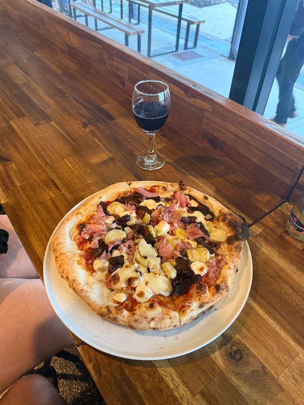A Pizza And A Glass Of Wine Are On A Wooden Table — Mumbo's Pizza'n'Pasta In Lismore, NSW
