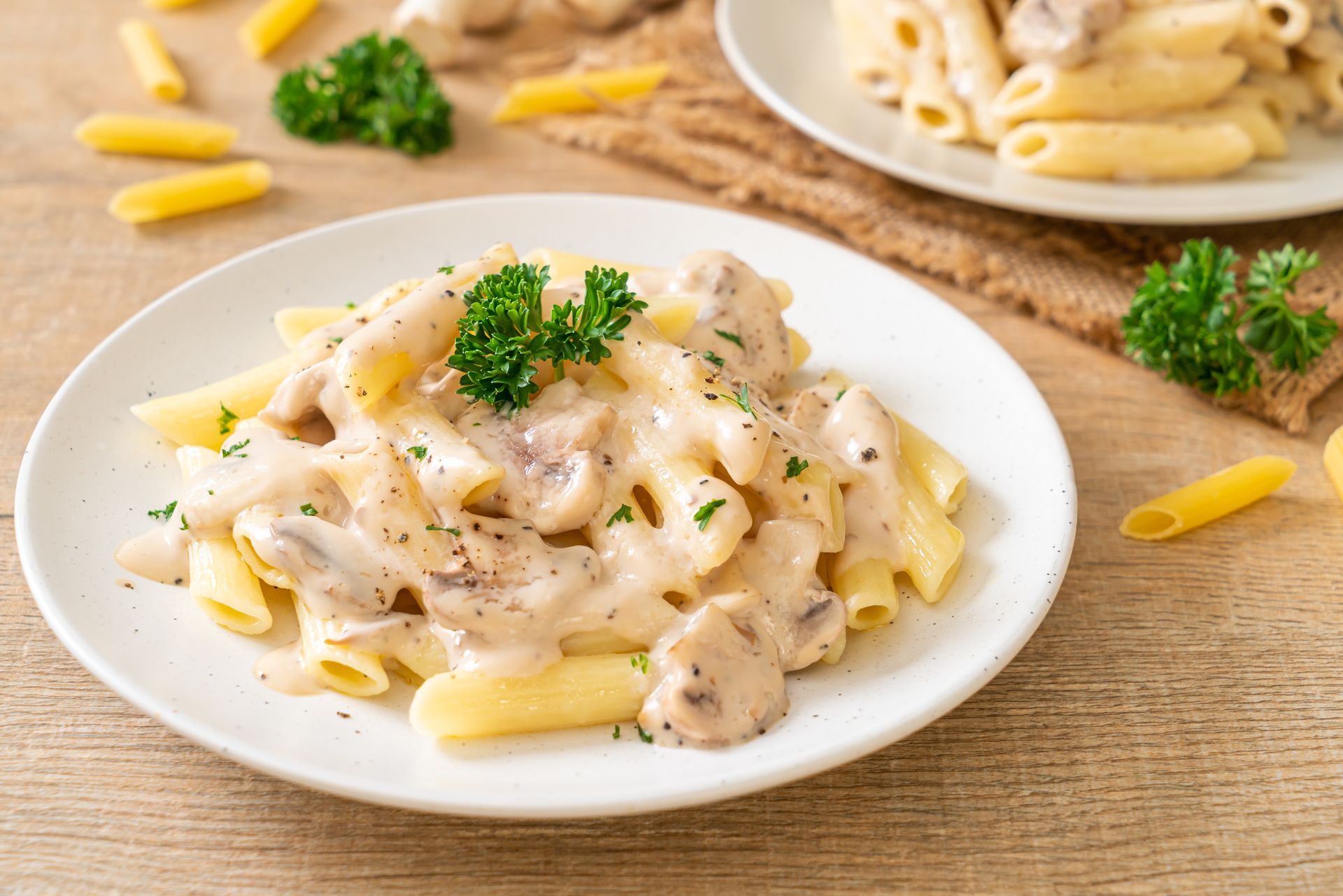 A Plate of Pasta With Mushroom Sauce on a Wooden Table — Mumbo's Pizza'n'Pasta In Lismore, NSW