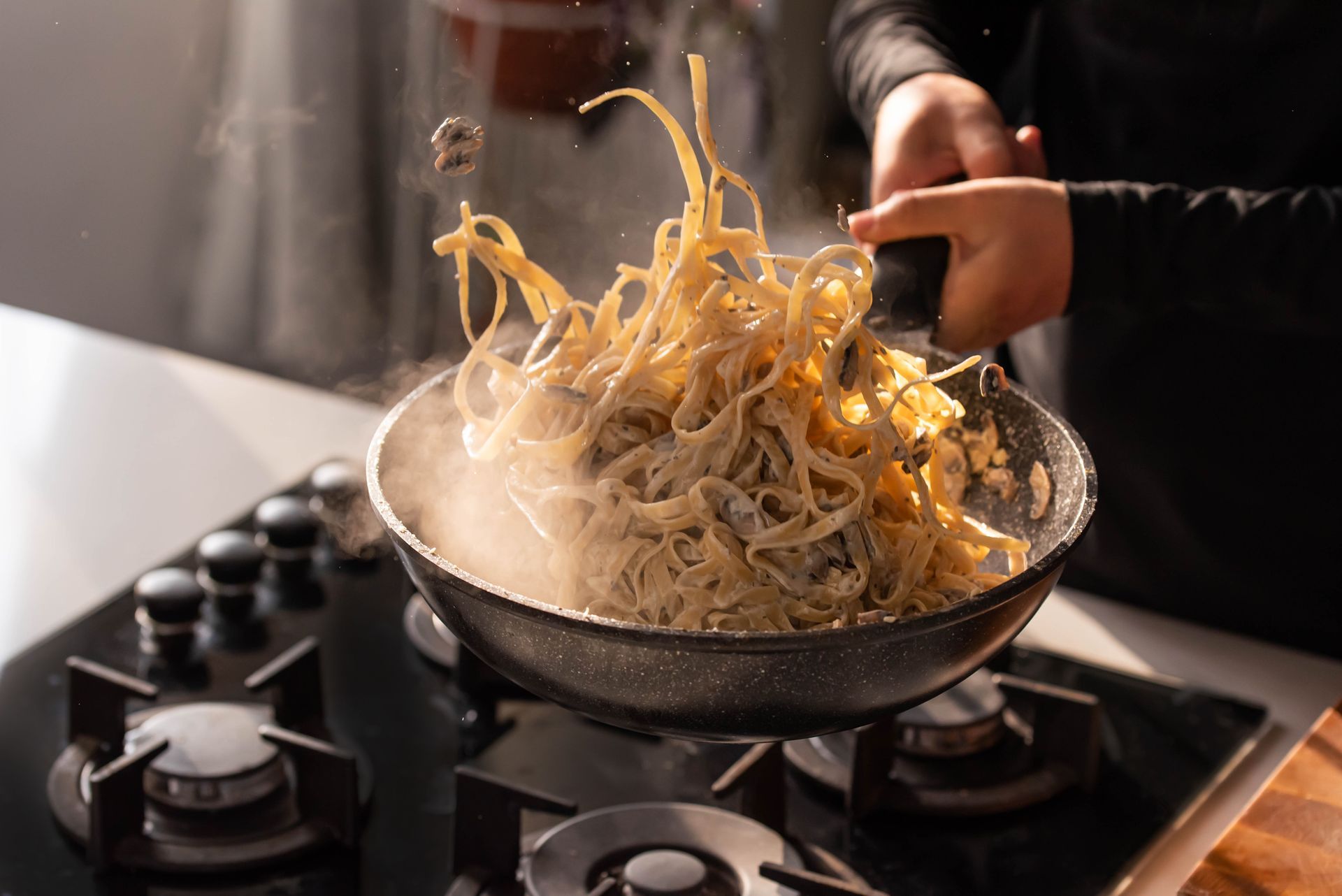 A Person is Cooking Noodles in a Frying Pan on a Stove — Mumbo's Pizza'n'Pasta In Lismore, NSW