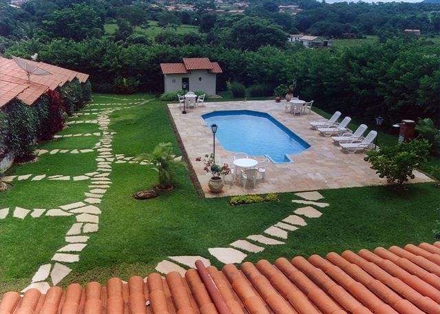 Pedra Lajão natural aplicada em pisos e caminhos externos, com grandes peças irregulares em tons de cinza, verde e bege integradas ao paisagismo tropical.