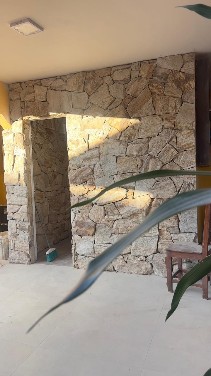 Pedra Amazon natural aplicada em fachadas, paredes e ambientes internos, com variações de tons terrosos, dourados e acinzentados.