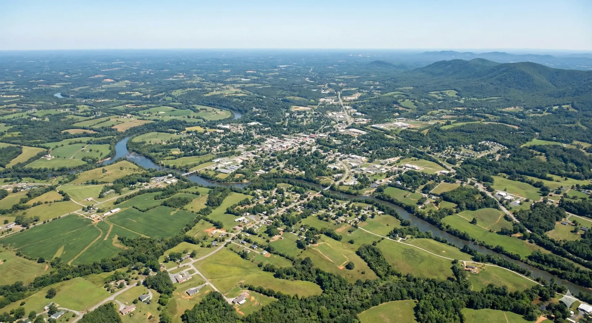 An aerial view of a river surrounded by trees and grass