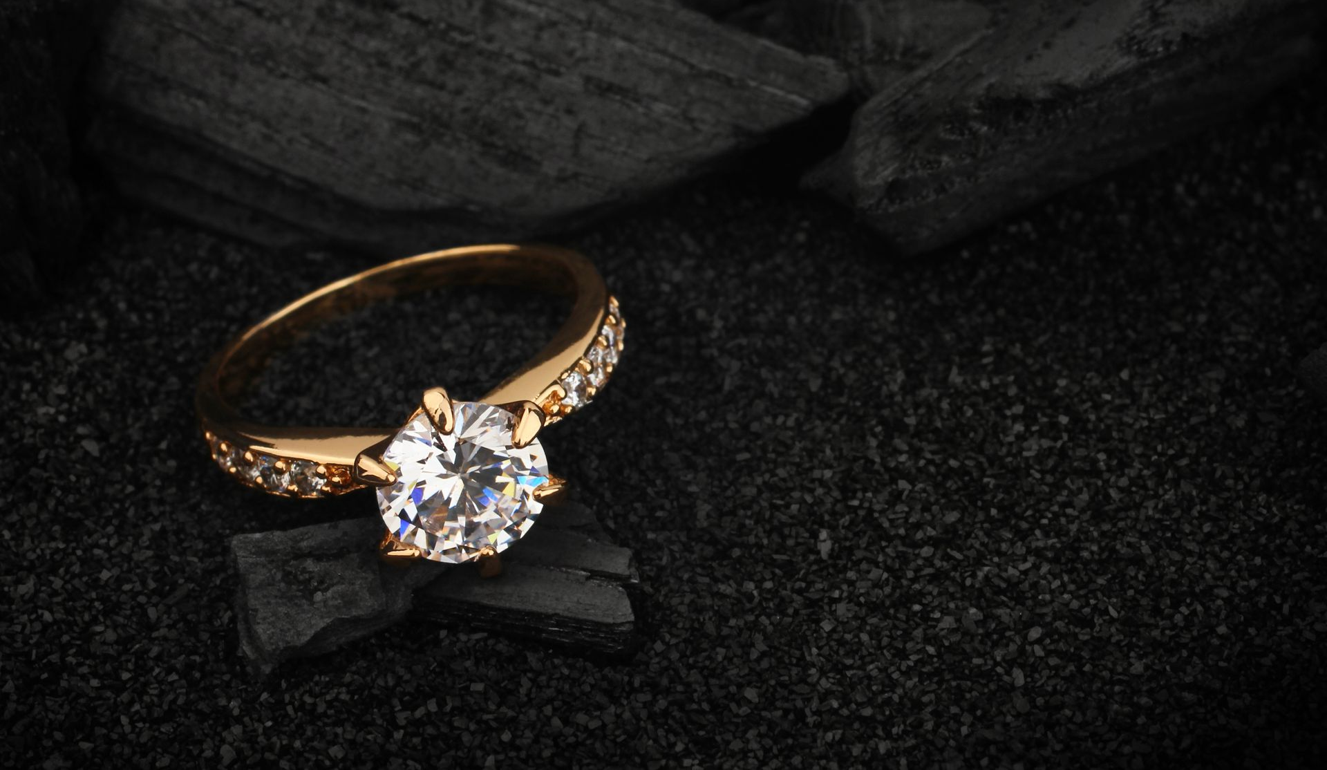 Gold ring with a sparkling solitaire diamond on a dark textured background
