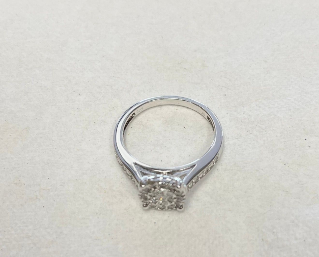 Silver ring with a square cluster diamond setting on a plain light background