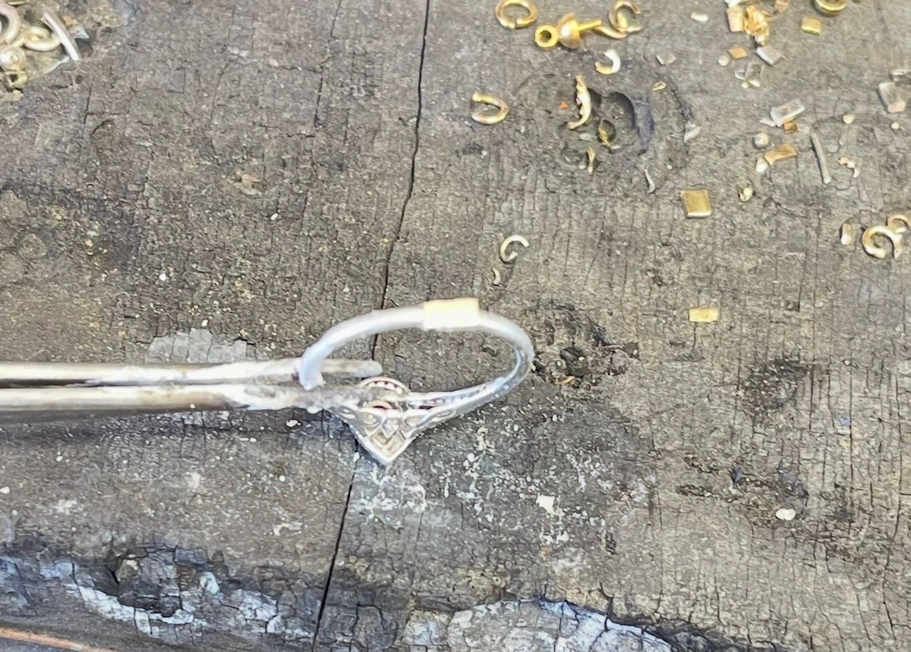 Broken white cable with looped end lying on rough concrete ground, with scattered small yellow debris.