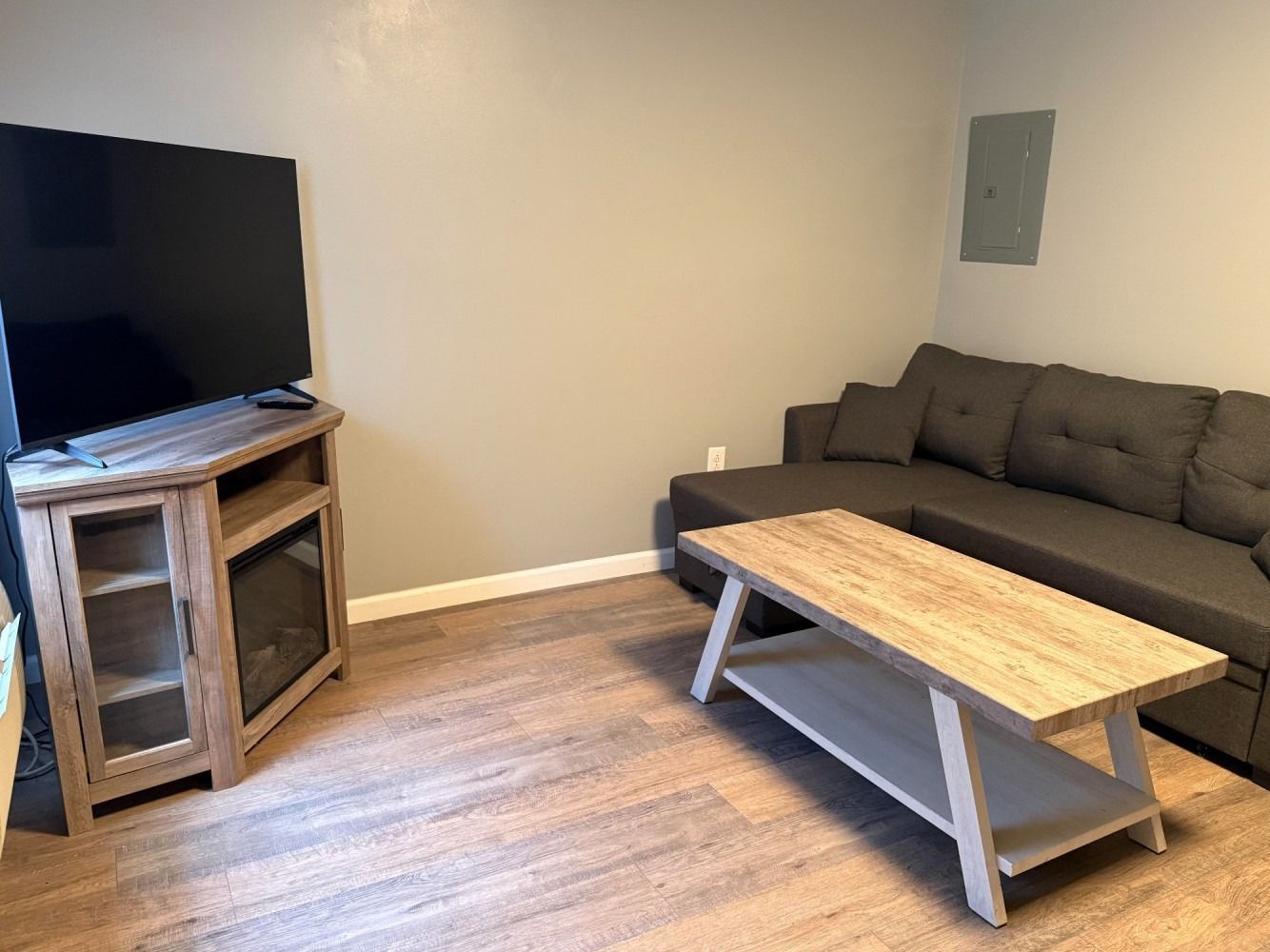 Living room with a gray sofa, wooden coffee table, TV, and light wood flooring