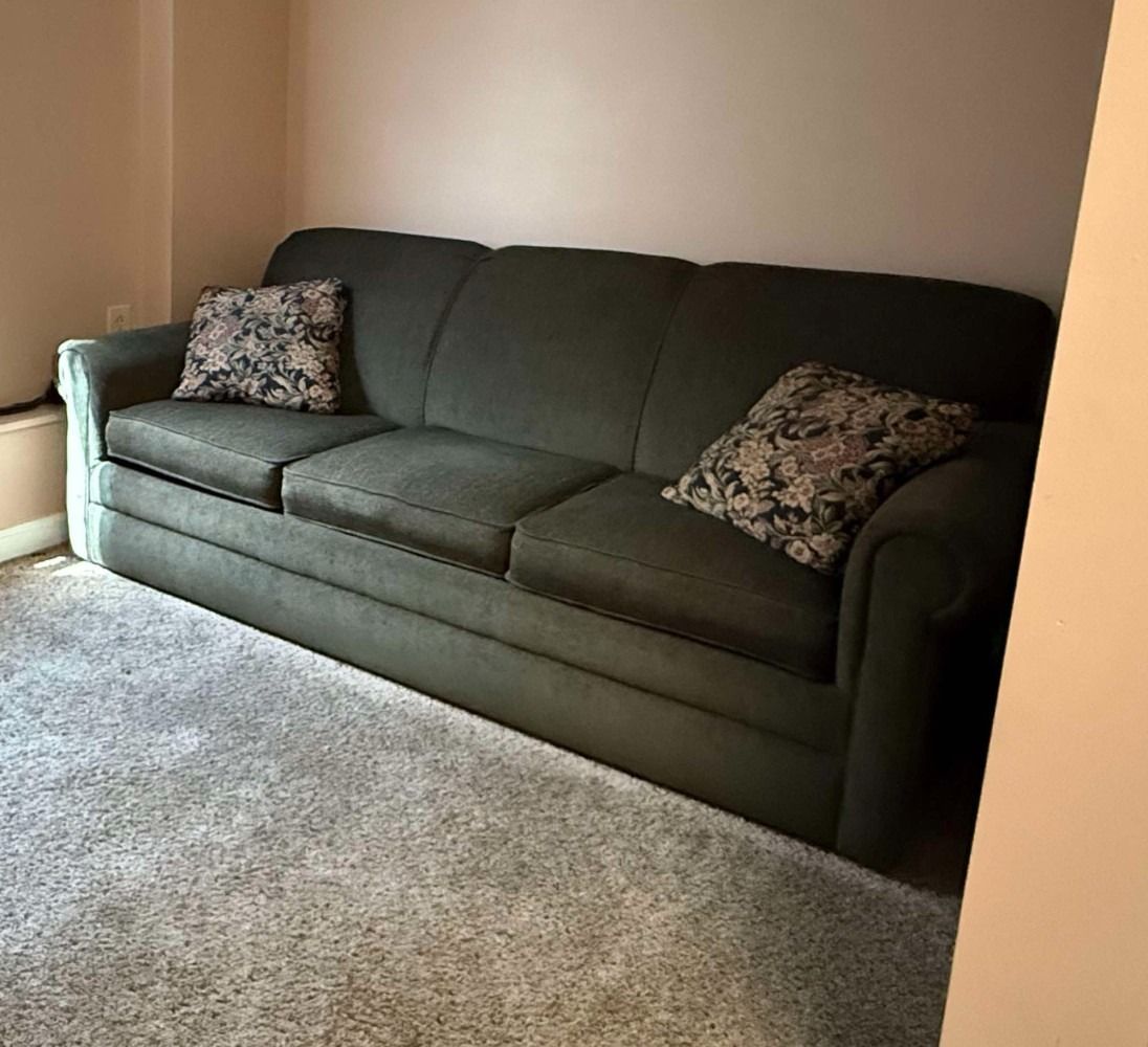 Dark green sofa with patterned pillows in a beige living room