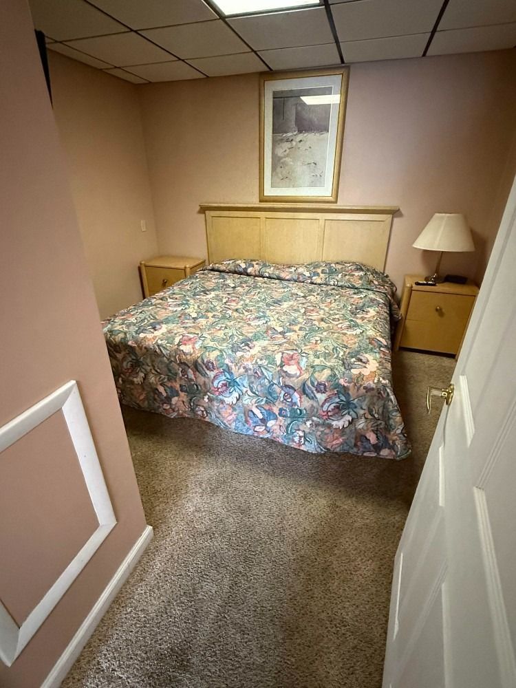 Small bedroom with a bed, nightstand lamp, and window under a sloped ceiling.
