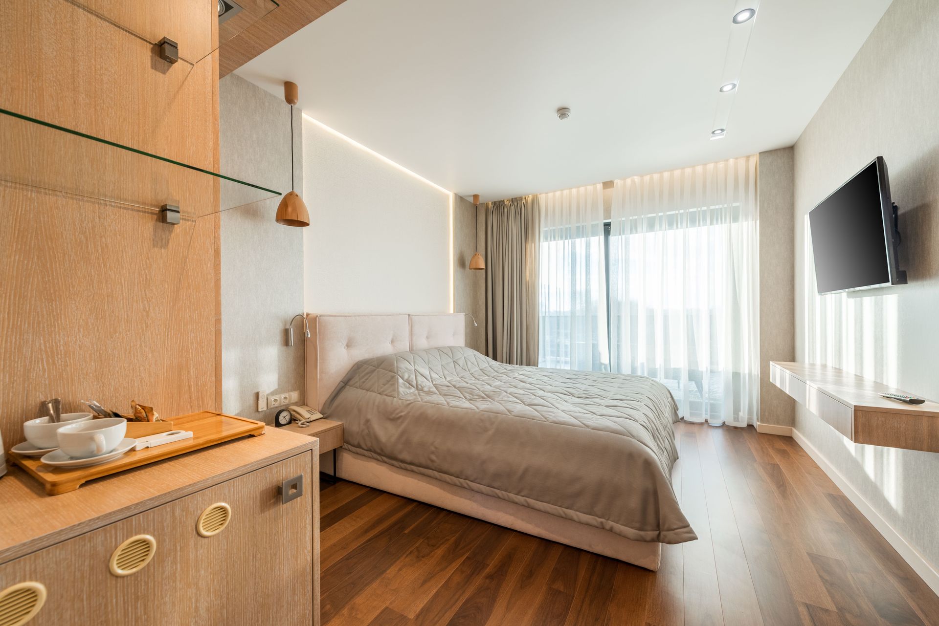 Pátio moderno de resort com uma pequena piscina, espreguiçadeiras, plantas em vasos e palmeiras com vista para a água.