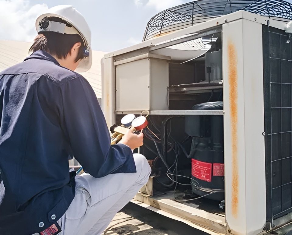 A Man Is Kneeling Down In Front Of An Air Conditioner — South Coast Refrigeration & Air Conditioning In Bomaderry, NSW