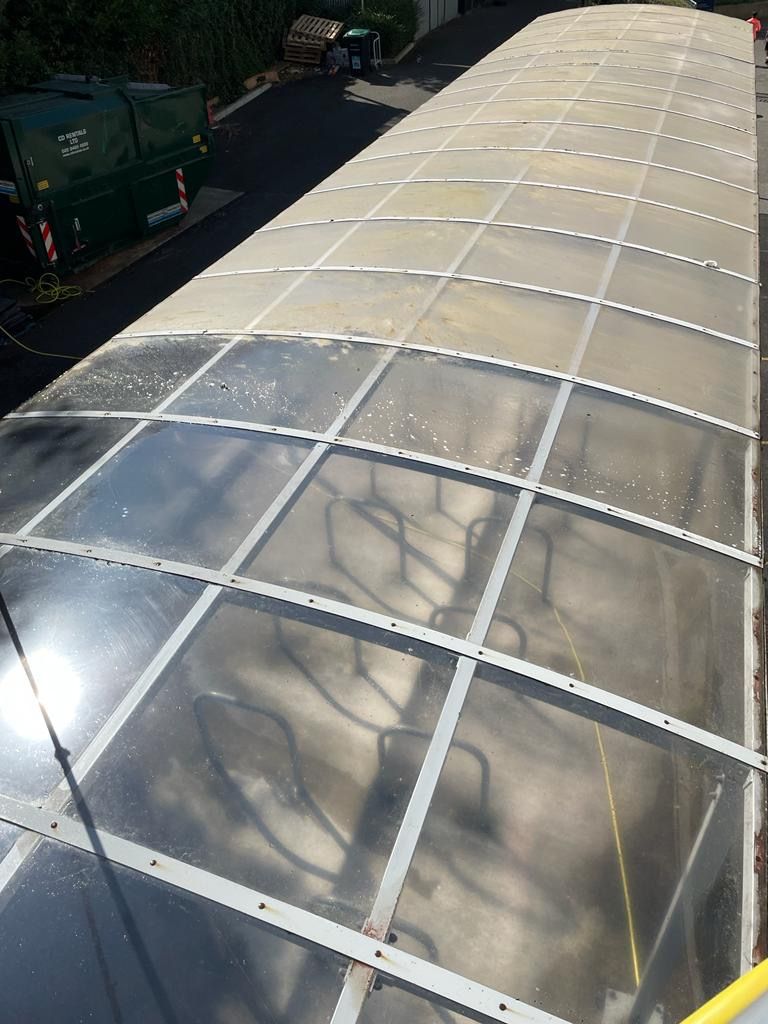 Overhead view of a long, clear-roofed structure with metal supports, possibly a bus shelter or walkway.