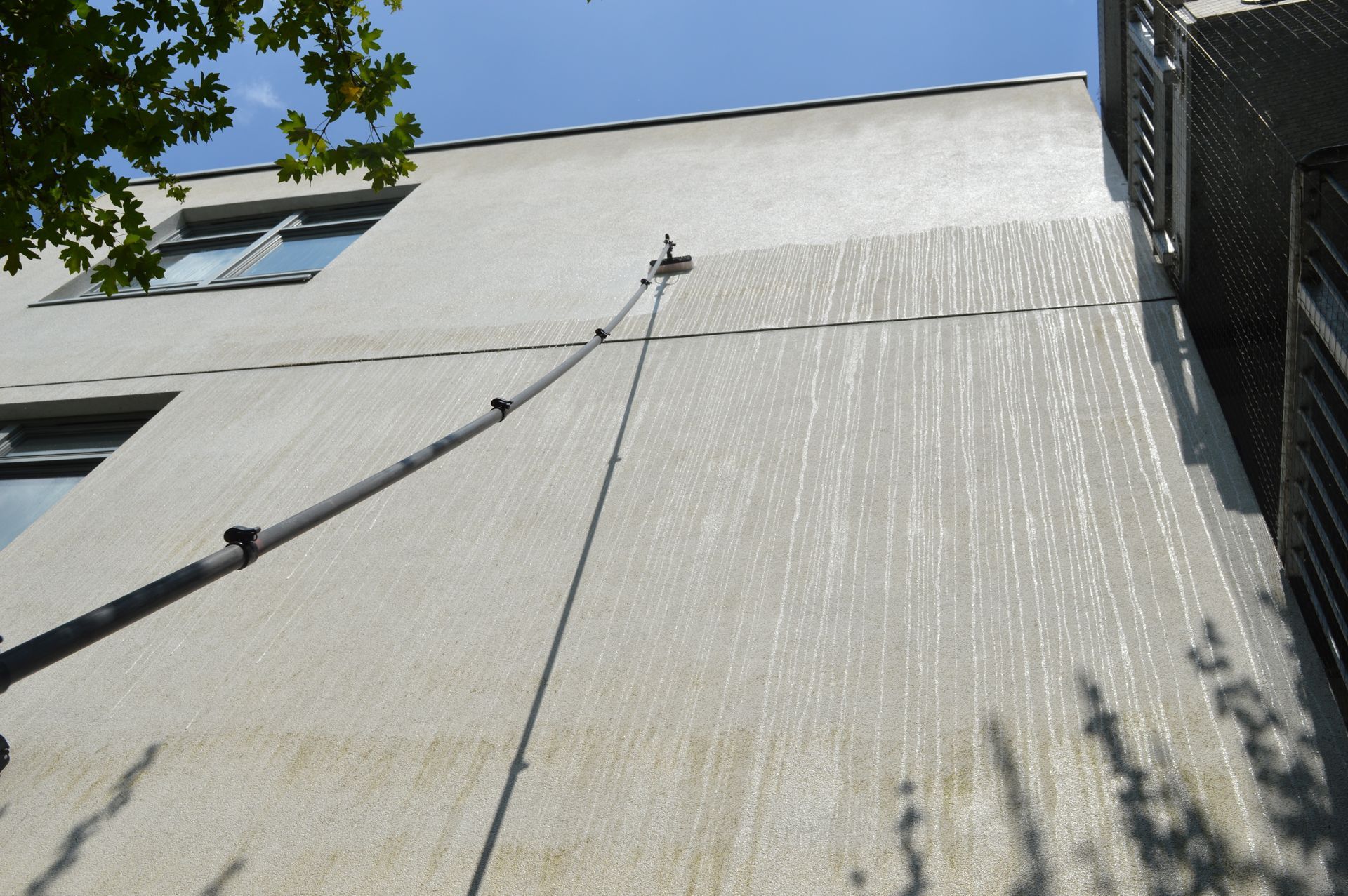 Building exterior with water streaks from cleaning. A long pole is leaning against the building.