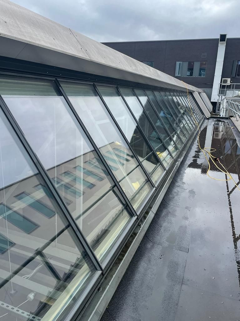 Professional window washer demonstrating the best way to clean windows on a commercial building using a safety harness and bucket