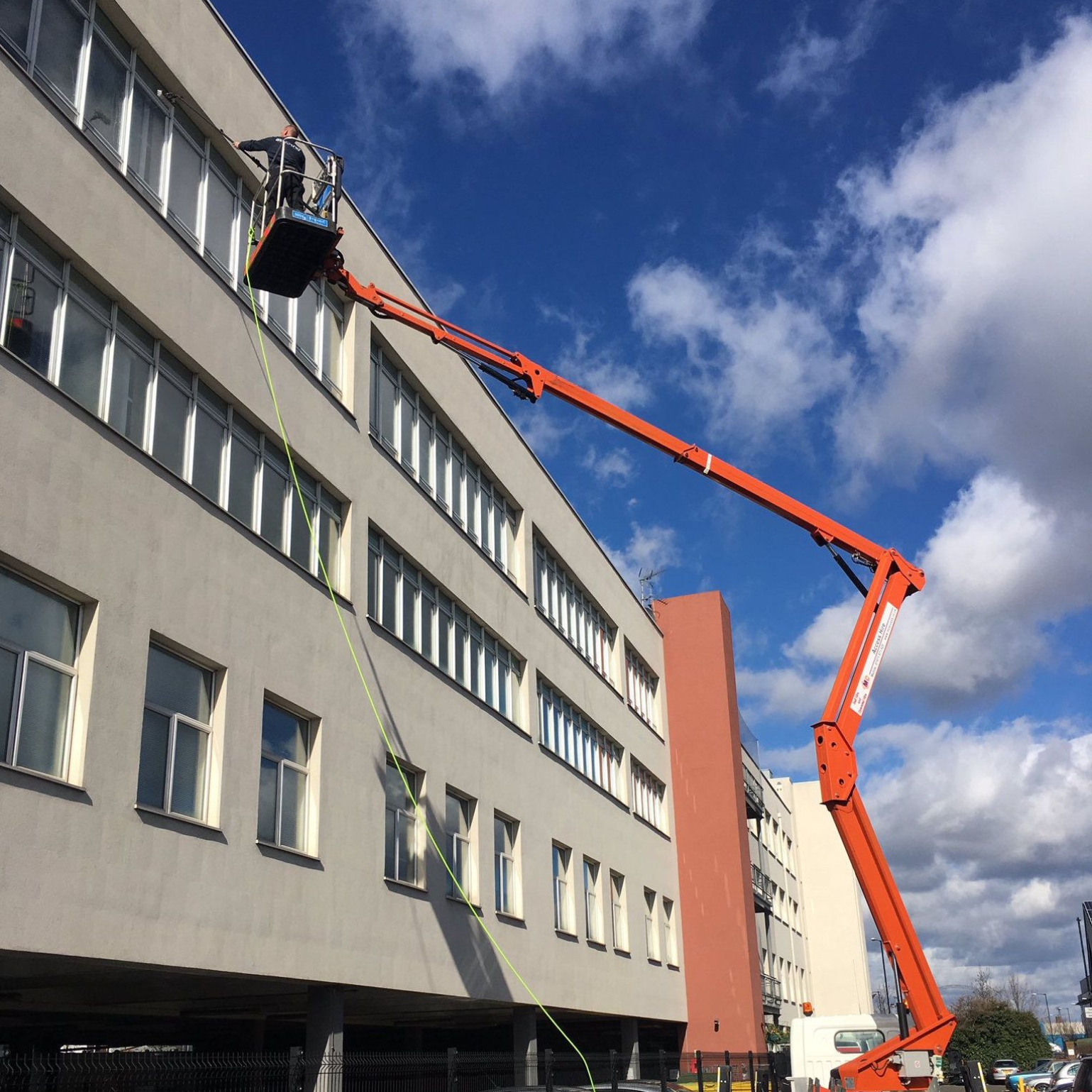Large boom lift with operator delivering high rise window cleaning to windows on a building in hove