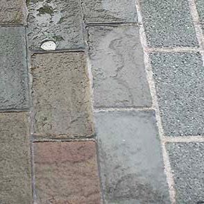 Close-up view of weathered, rectangular paving stones in various muted colors.