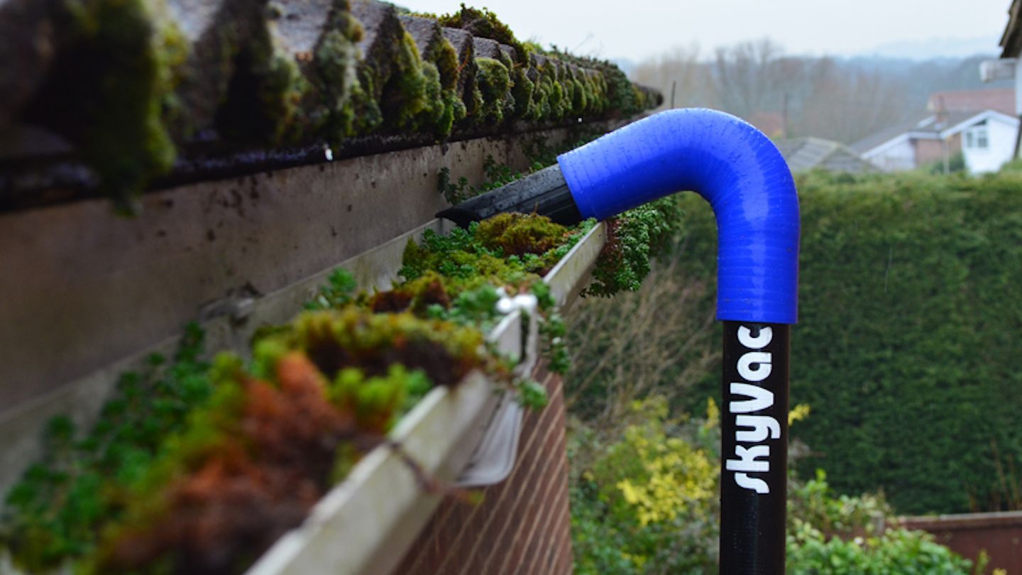 SkyVac gutter vacuum cleaning a moss-filled gutter — how often should gutters be cleaned to prevent build-up like this.