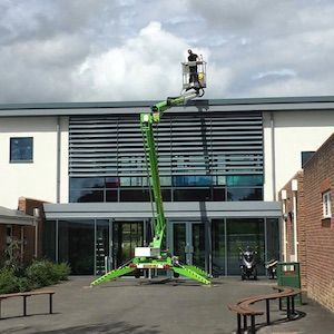 Man on a boom lift doing exterior cleaning services and gutter cleaning